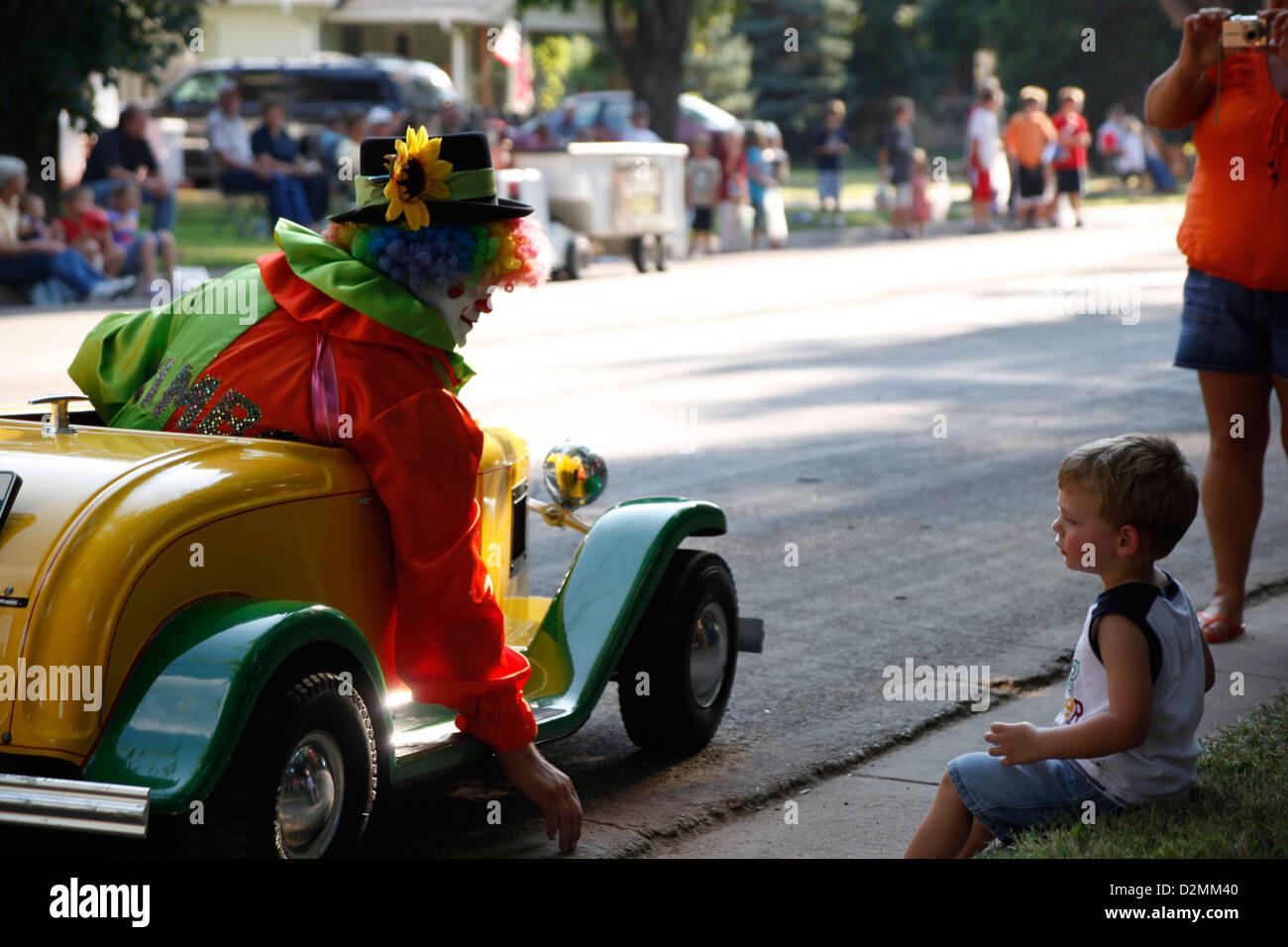 Colorful clown in a car talking to a little boy during a parade Stock Photo