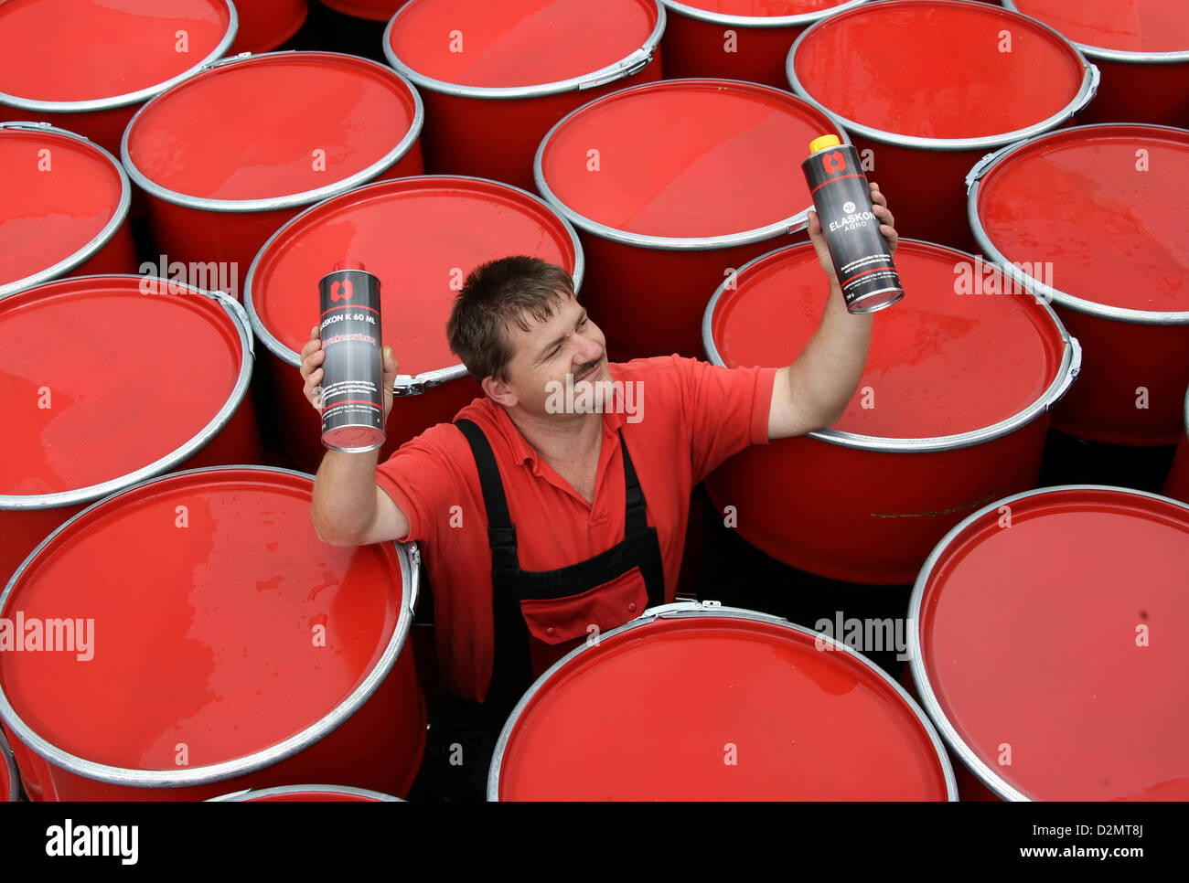 An employee of the company Elaskon is pictured standing between oil barrels and showing Elaskon products in Dresden, 25 July 2007. After reintroducing the car protection agent 'K60 ML', the company now also reintroduces the tractor protection agent 'Elaskon agro' to the market. The company was founded by the trade company Richter in Dresden in 1928 and used to be one of the biggest company in the chemical industry of the GDR. After the German Reunification, Elaskon focused on rope lubricants and other special products and in recent years also produces maintenance products for motor vehicles. P Stock Photo