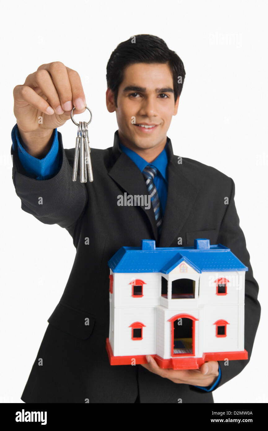 Real estate agent holding house keys and a model home Stock Photo Alamy
