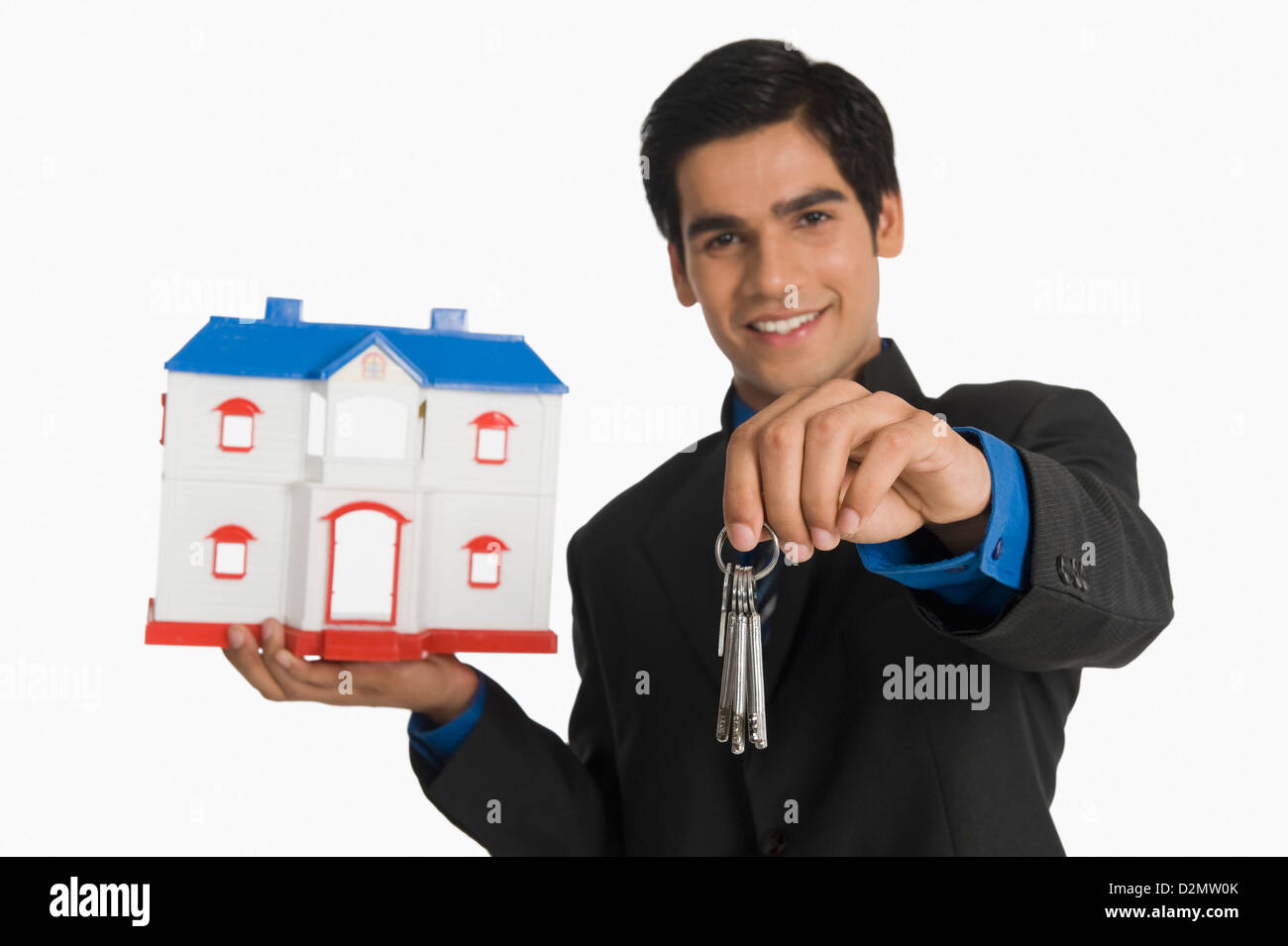 Real estate agent holding house keys and a model home Stock Photo - Alamy