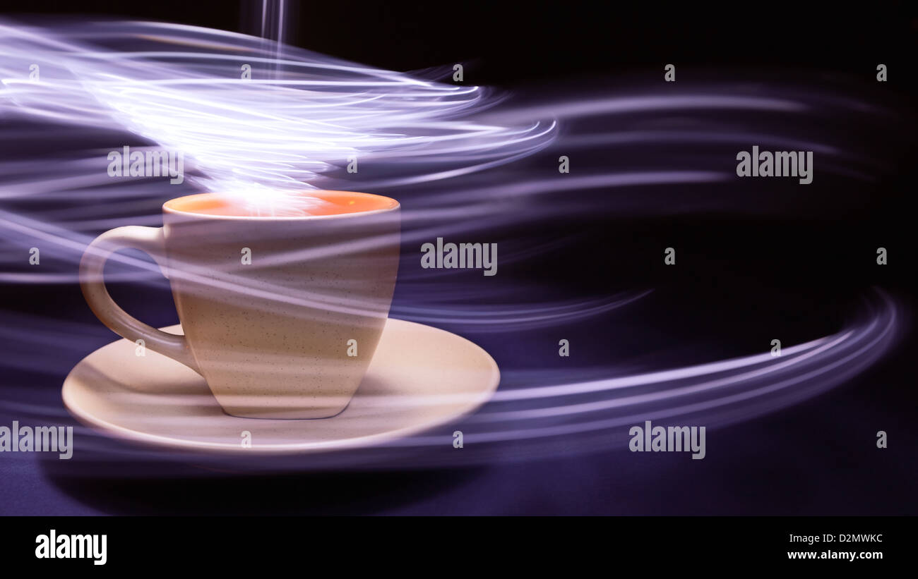 Cup of coffee on black and blue background with light trails above it and around the cup. Stock Photo