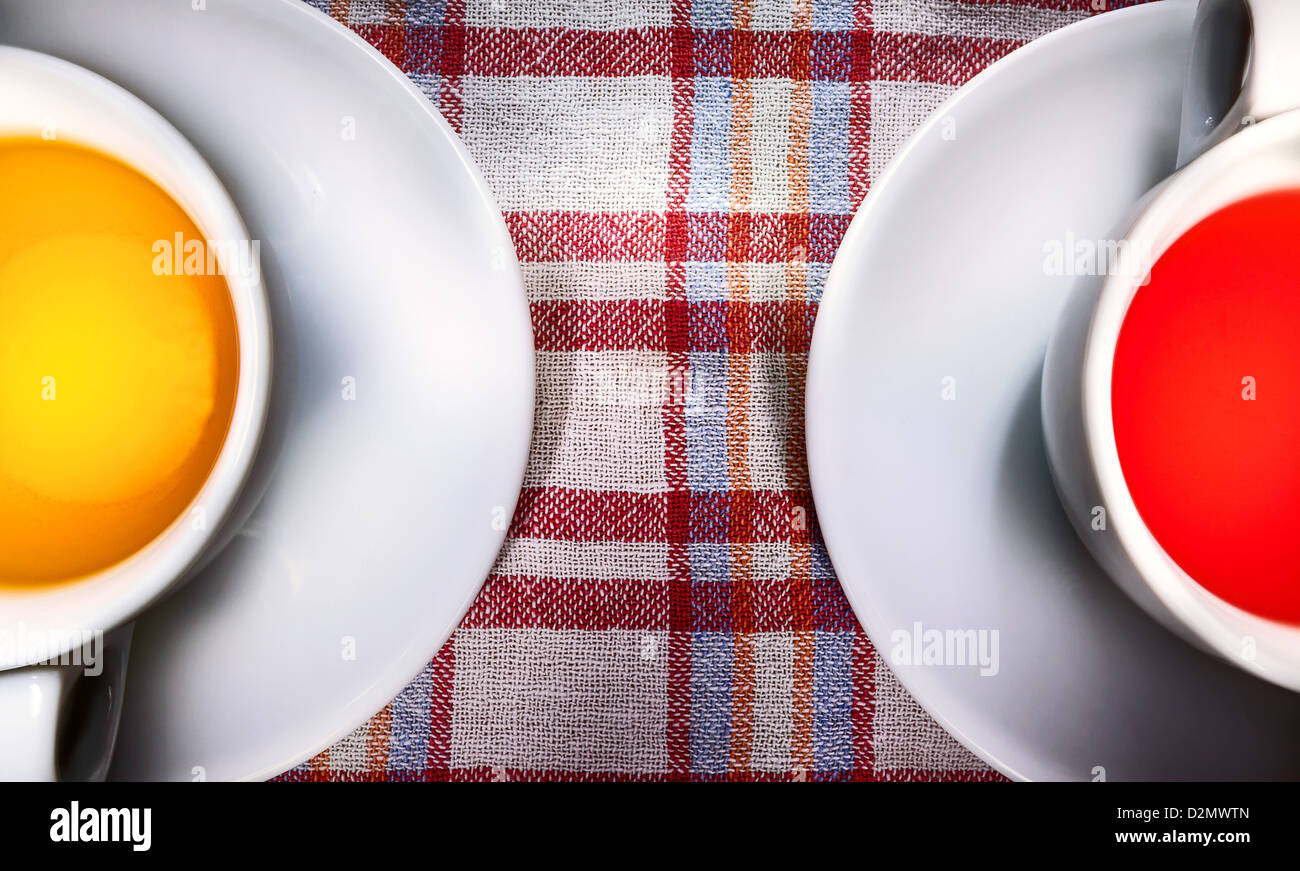Two white cups of tea, with one red and one orange tea. Stock Photo