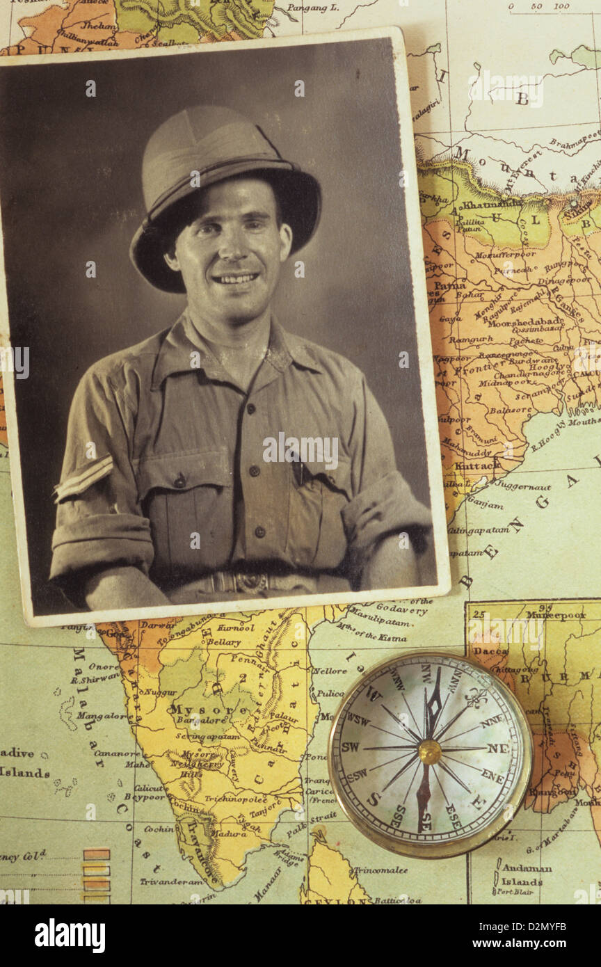 Black and white photograph of man in tropical military uniform placed with compass on map of India Stock Photo