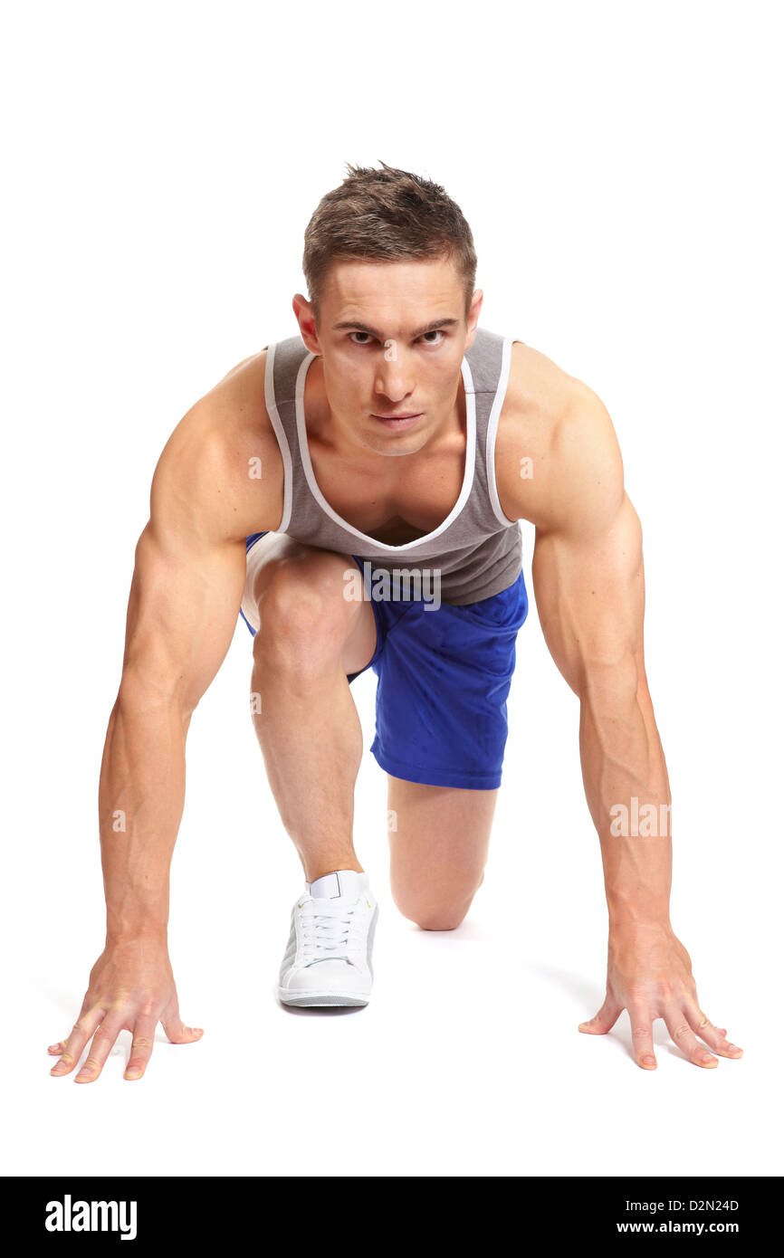 Muscular young man in starting position and ready to race in sports outfit on white background Stock Photo