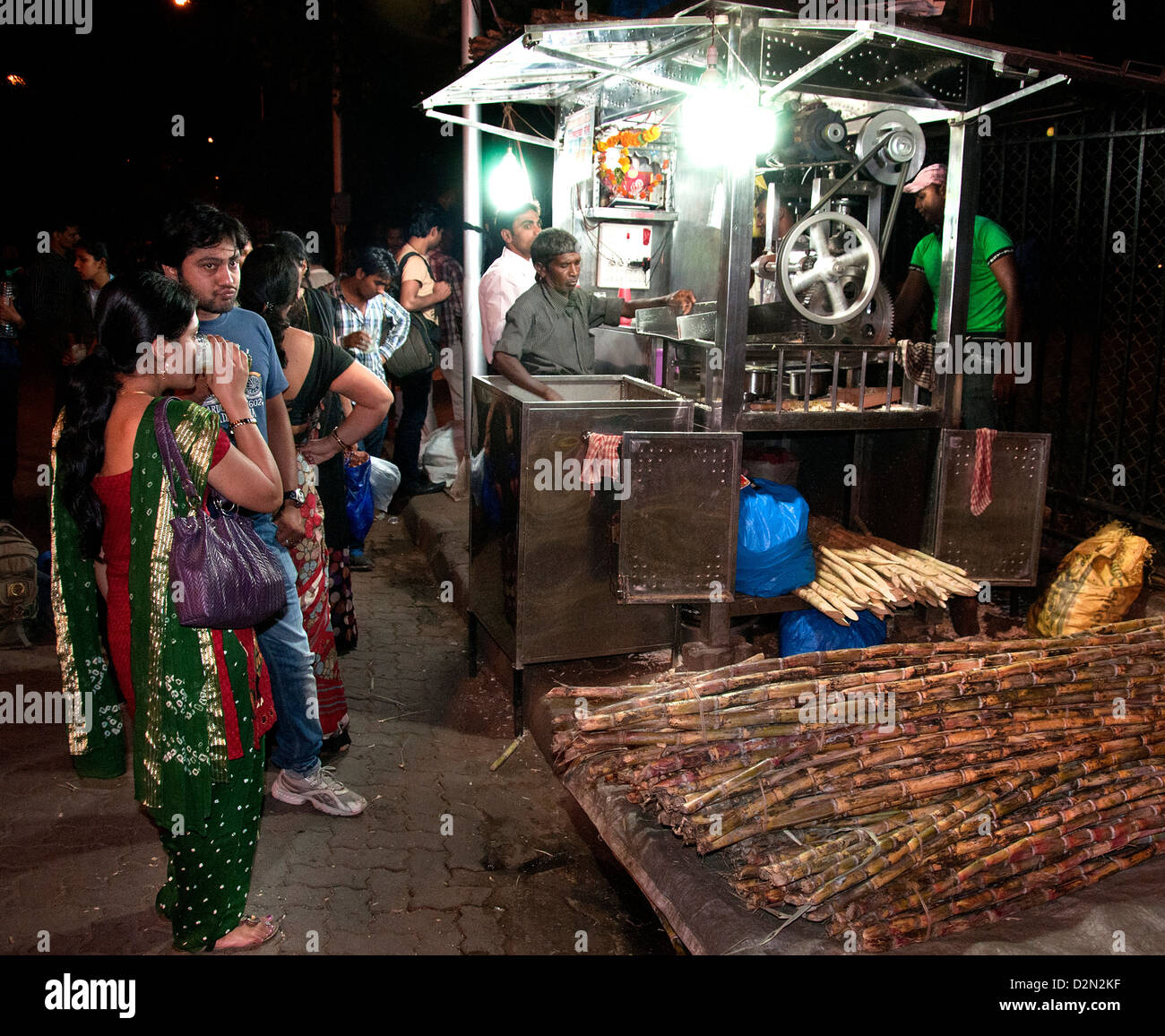 Young men operating sugar cane juice squeezer Mumbai ( Bombay ) India Stock Photo