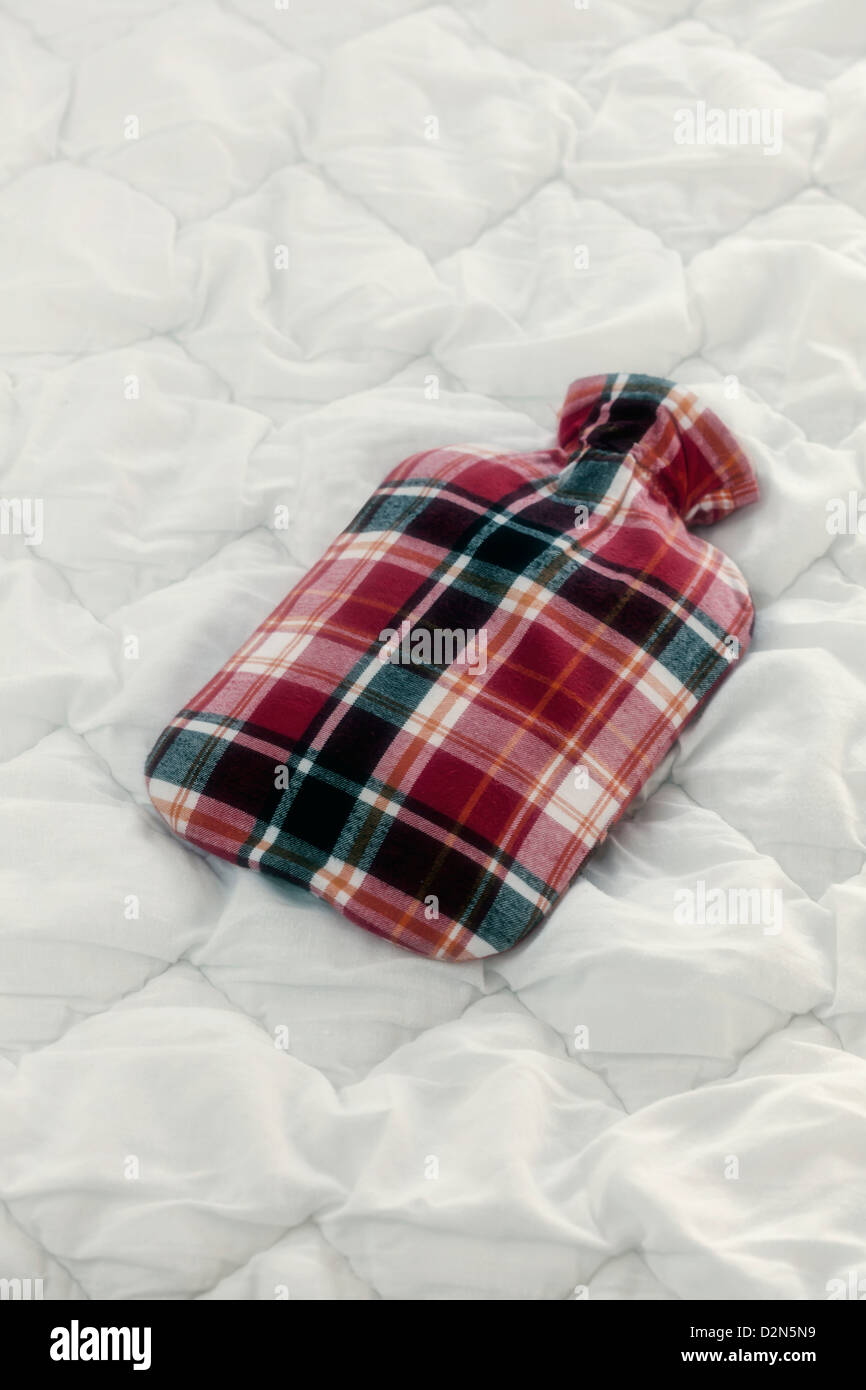 a vintage hot-water bottle on a duvet Stock Photo