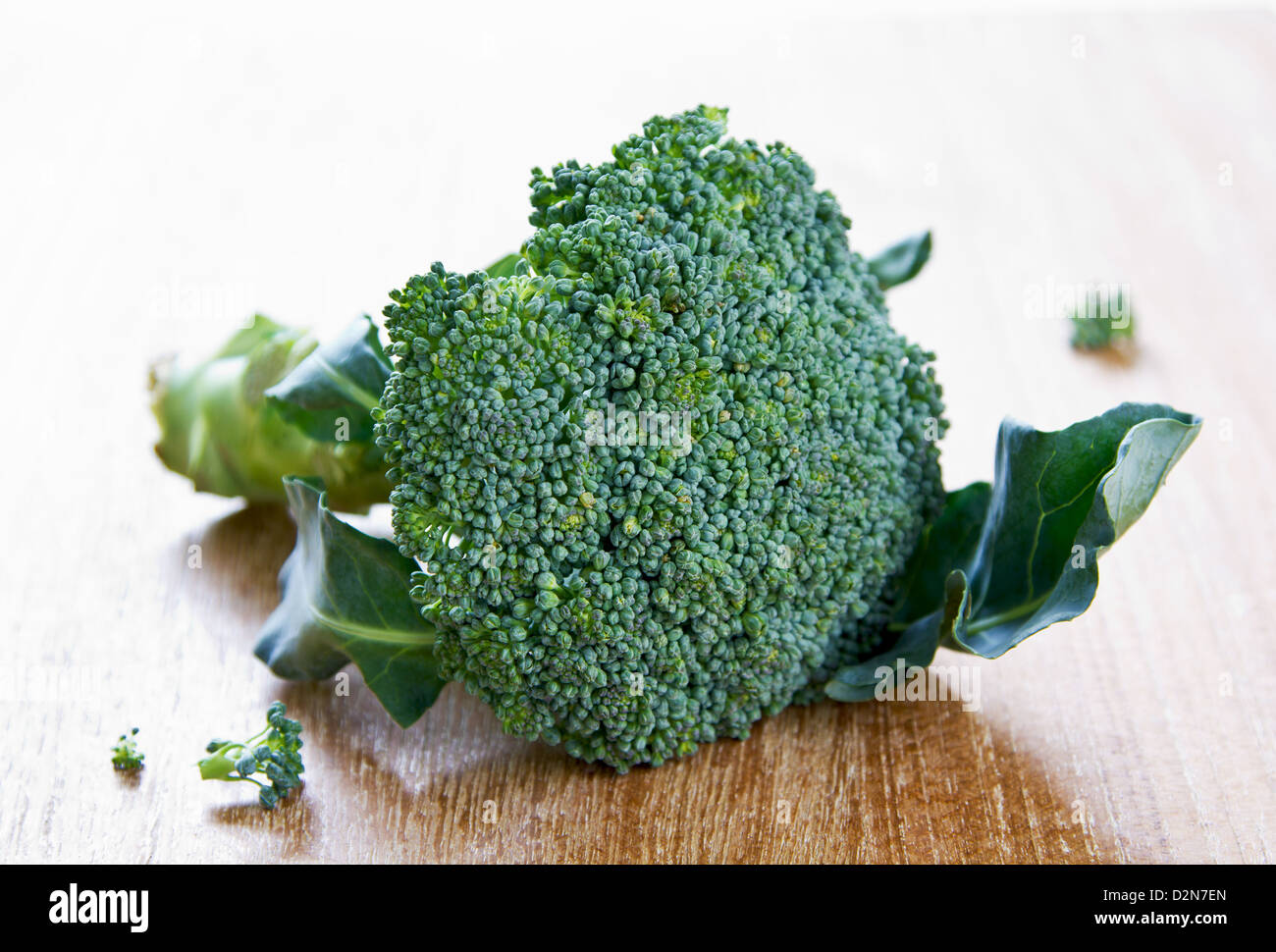 Fresh uncooked broccoli in colander and chopping board Stock Photo