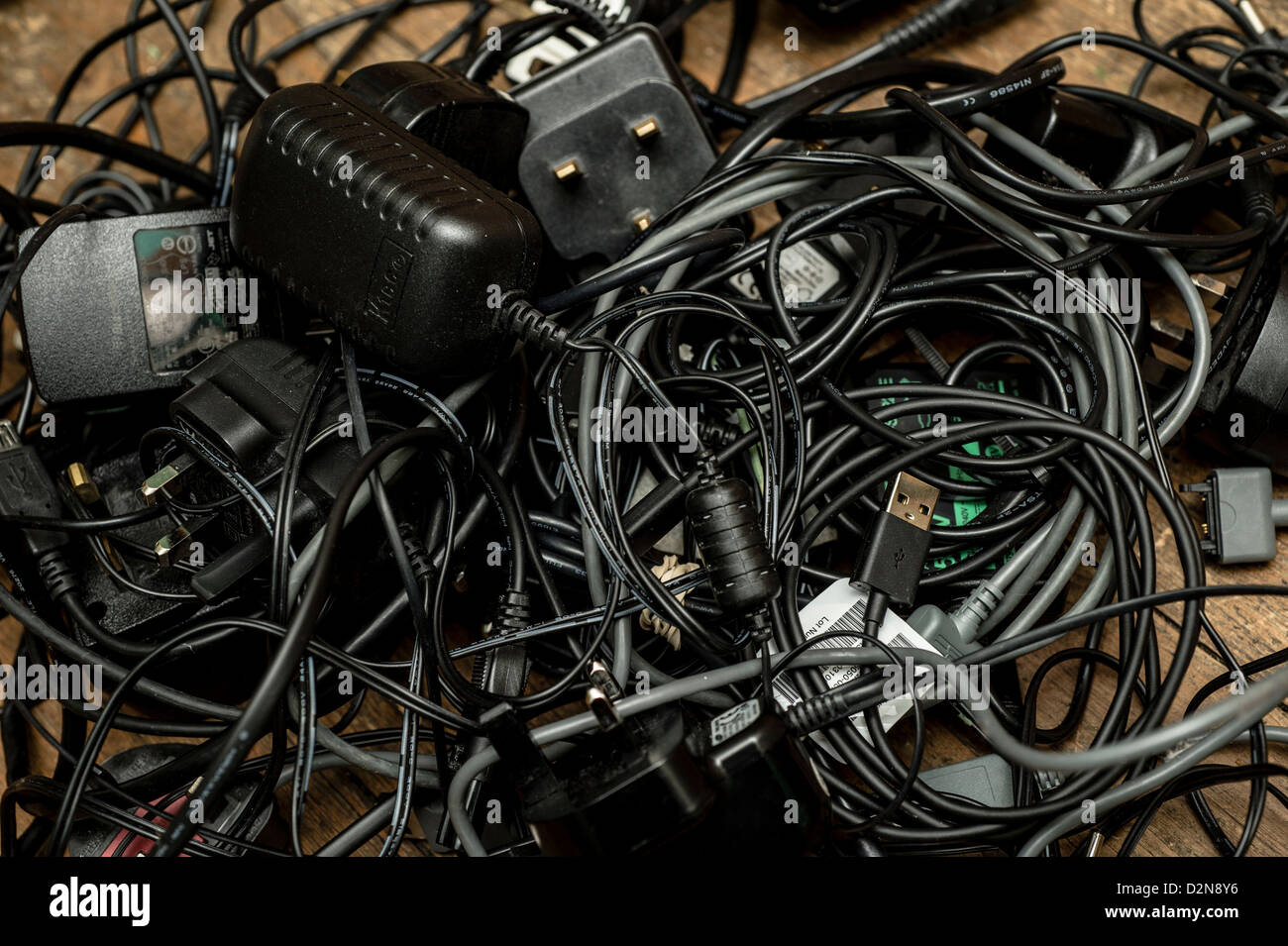 A pile of old redundant mobile phone chargers and other electrical power adaptors and cables leads UK Stock Photo