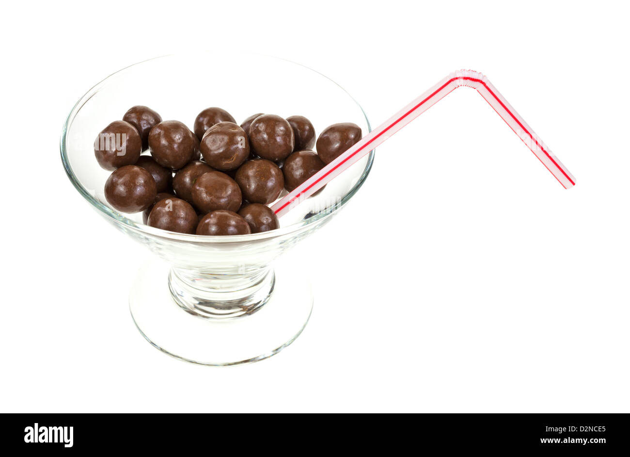 A cocktail glass with milk chocolate balls and a straw on a white background. Stock Photo