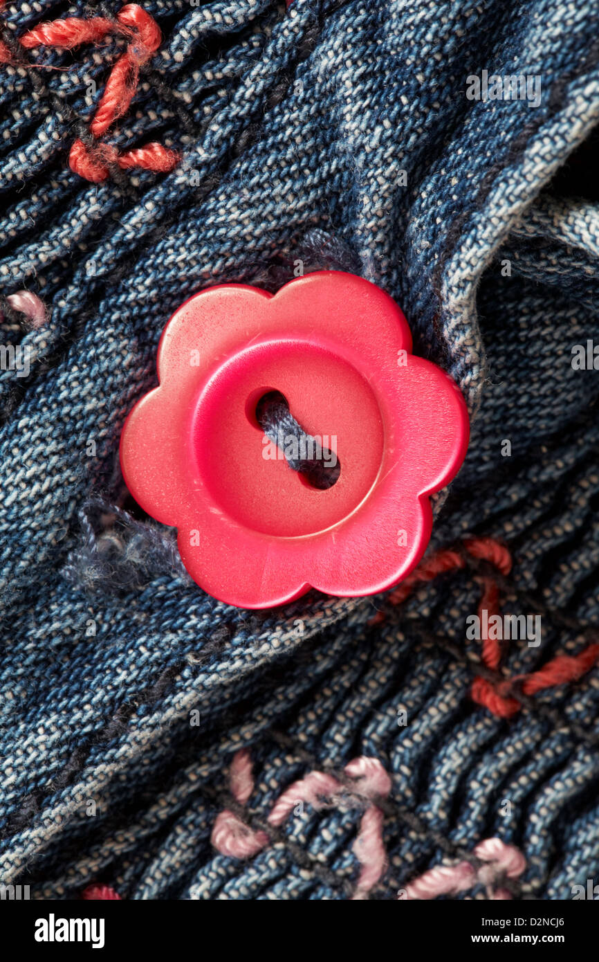 daisy shaped red button on little girl's denim dress Stock Photo