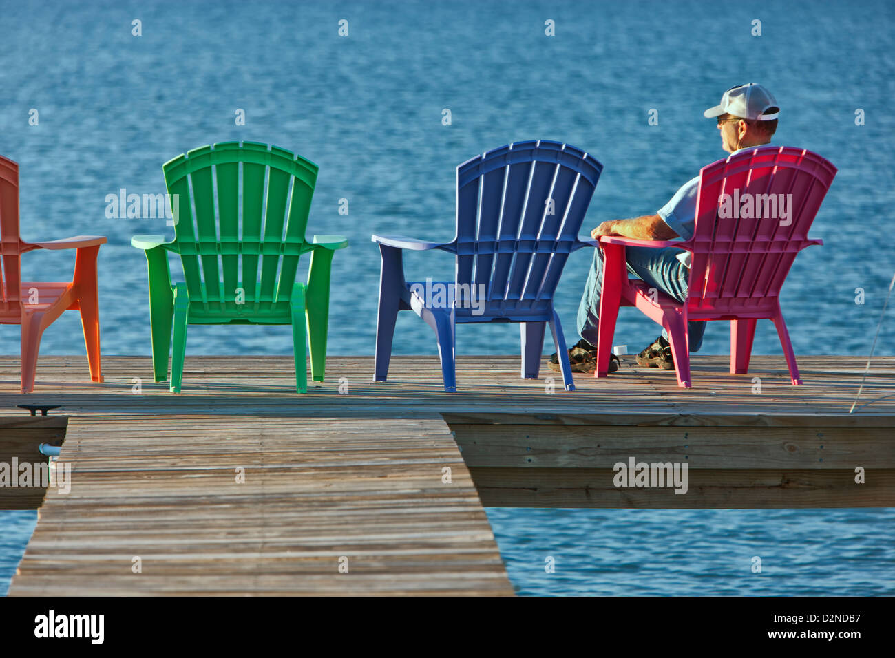 Senior male sitting red plastic deck chair, fishing pier Stock Photo - Alamy
