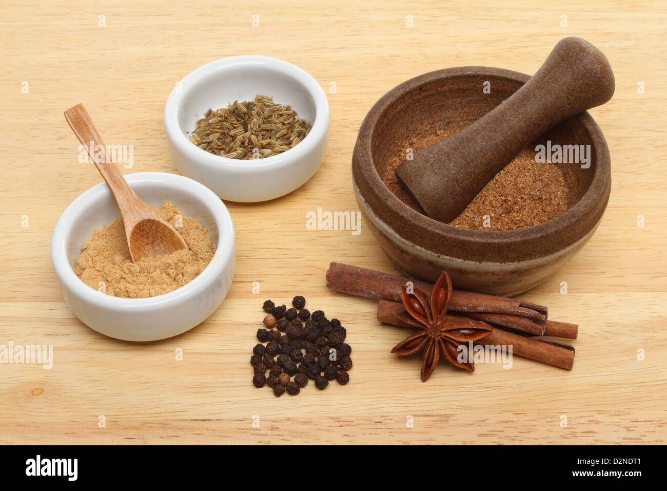 Ingredients for Chinese five spice with ramekins and a pestle and mortar on a wooden board Stock Photo