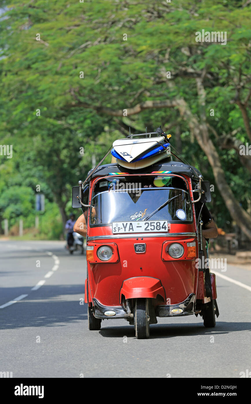 Tuktuk with surfboards loaded on the roof transports surfers back to Weligama Bay after a surfing trip. Stock Photo