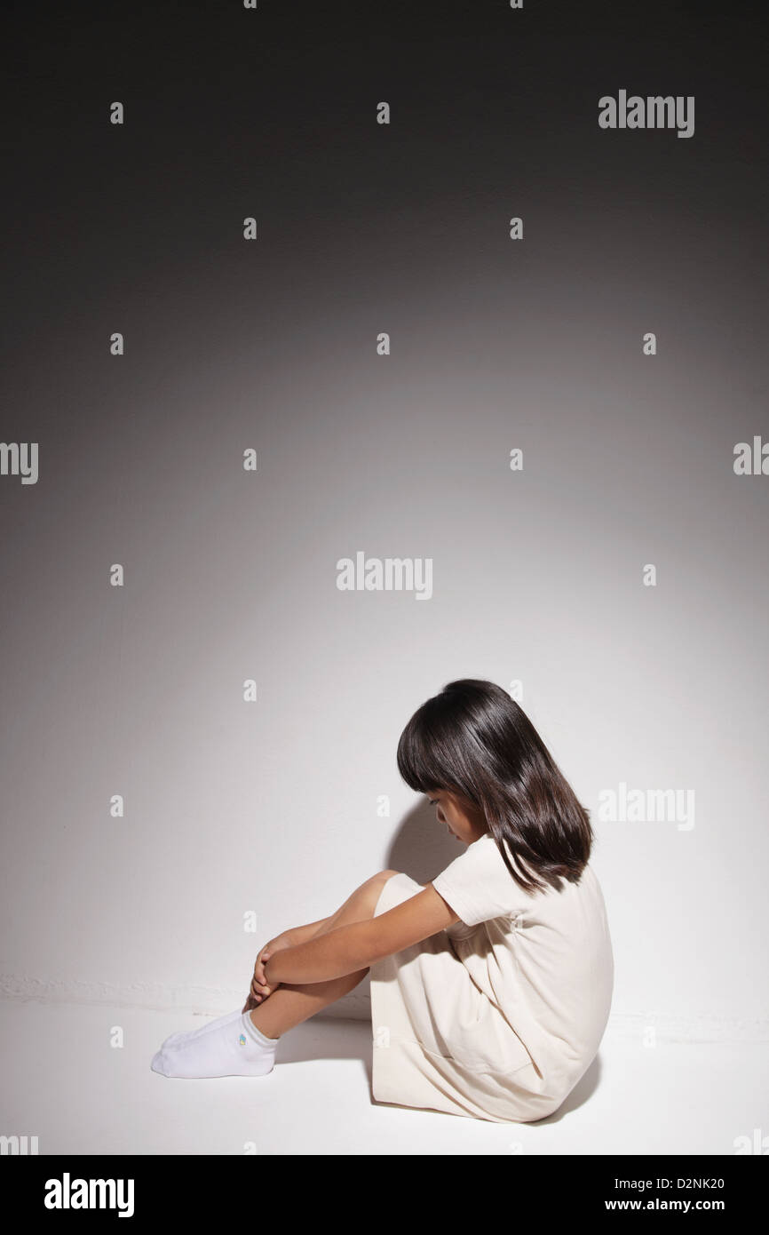 Sad girl in a white dress sitting on the floor Stock Photo - Alamy