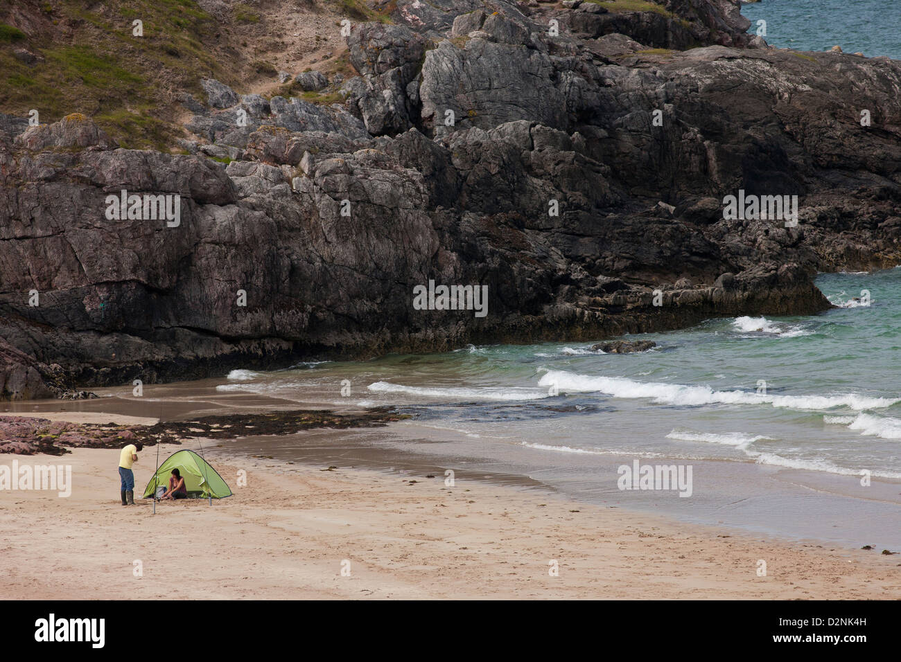 A couple shelter from the wind while fishing of a remote Scottish Beach in the Sutherland region close to Cape Wrath Stock Photo