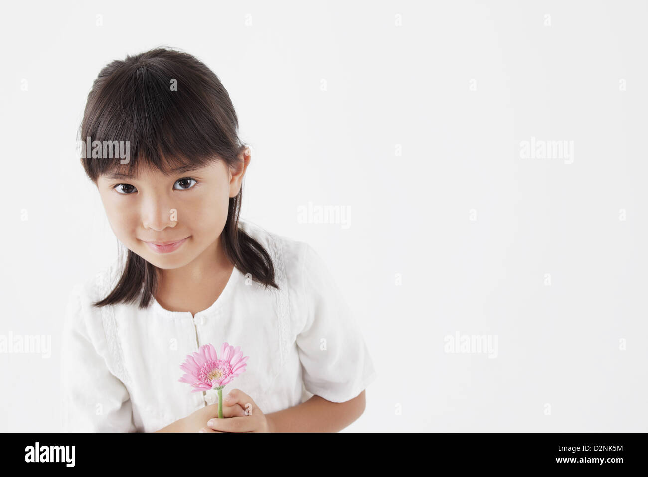 Girl in a white dress holding a pink flower Stock Photo - Alamy