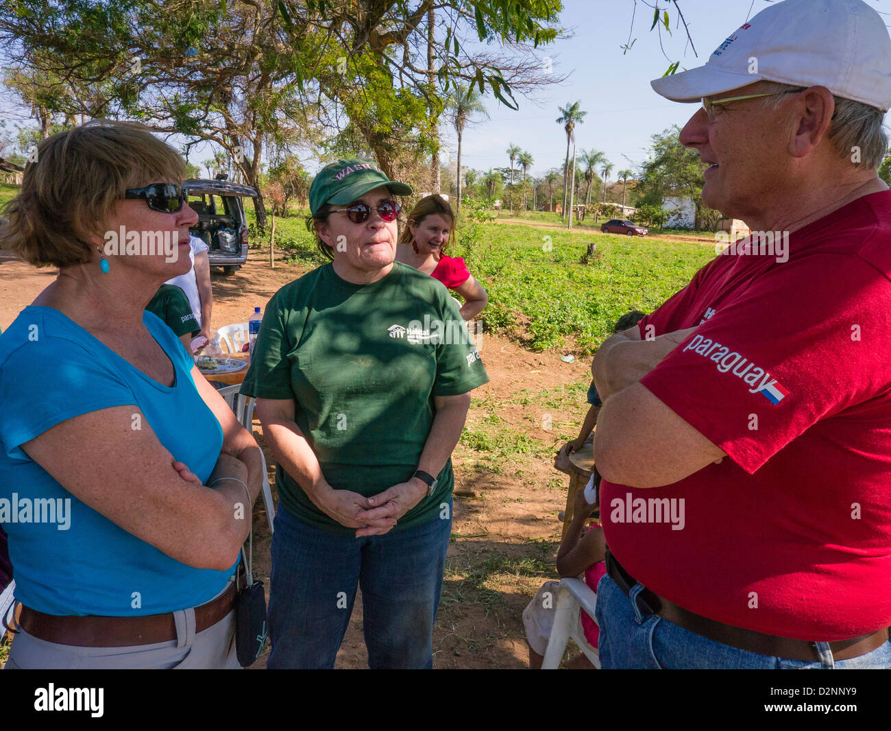 3 adult volunteers from the USA for Habitat for Humanity stand and talk at a work site in Luque, Paraguay. Stock Photo