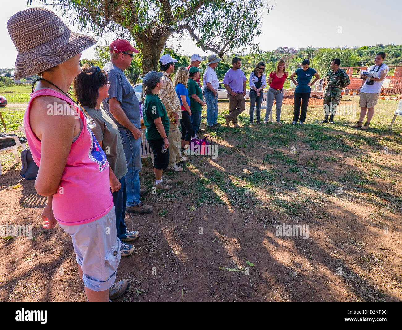 Adult volunteers for Habitat for Humanity stand in a circle at a ceremony for their work in building a house in Luque, Paraguay. Stock Photo
