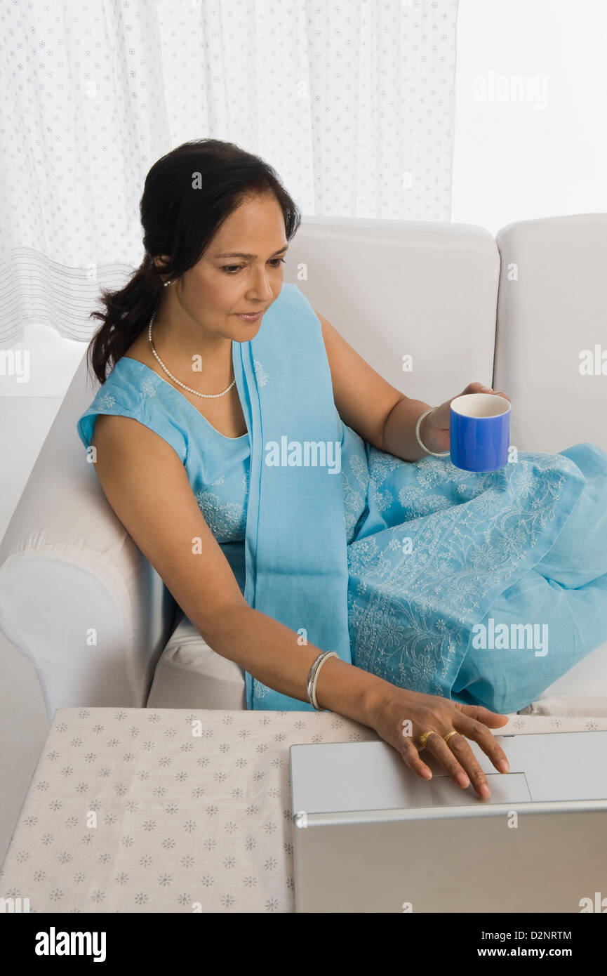 Woman sitting on a couch and using a laptop Stock Photo - Alamy