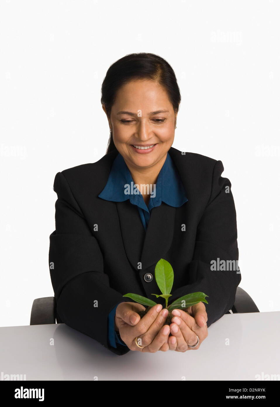 Businesswoman holding a plant and smiling Stock Photo - Alamy