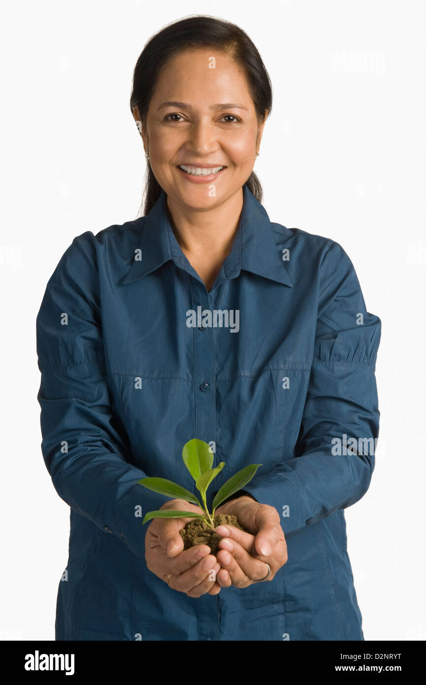 Woman holding a plant and smiling Stock Photo - Alamy