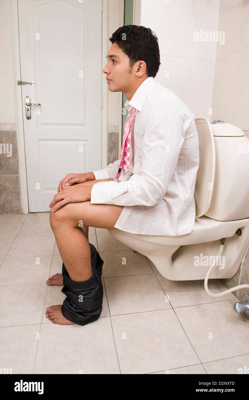 Man sitting on a toilet seat Stock Photo
