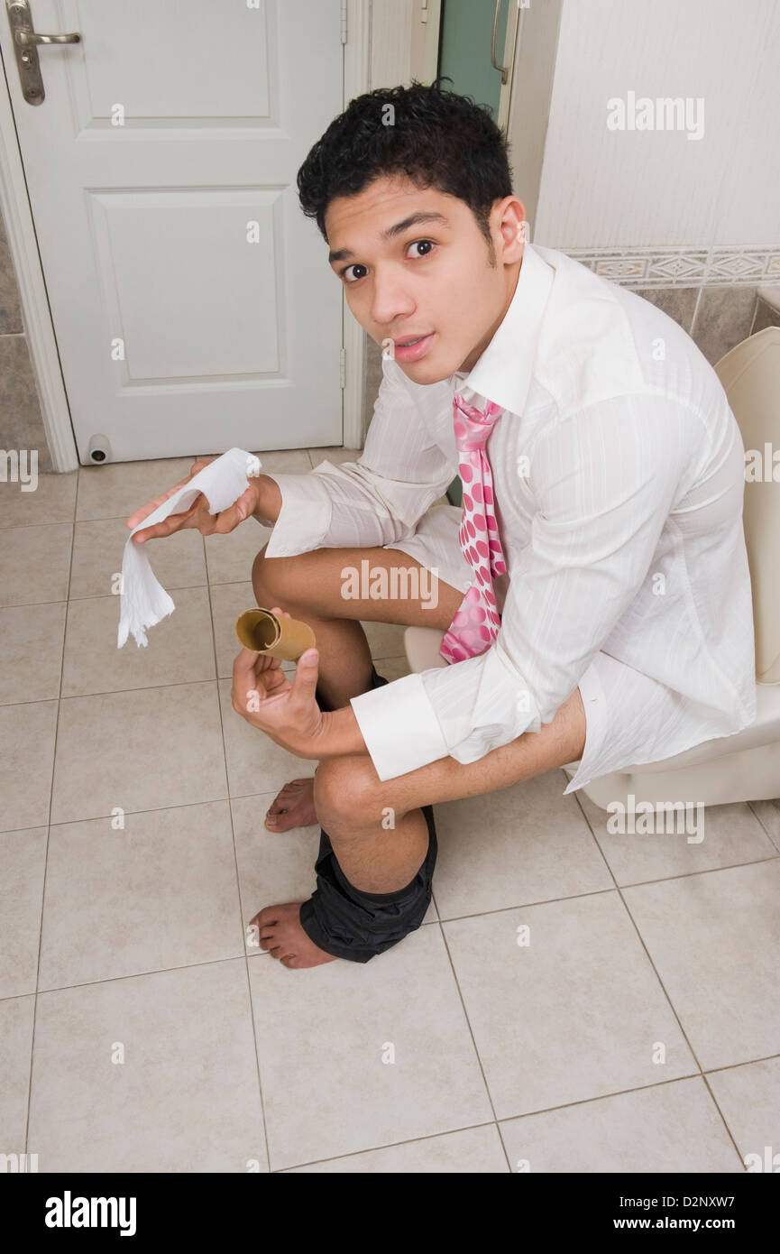 Man sitting on a toilet seat and showing a toilet paper Stock Photo Alamy