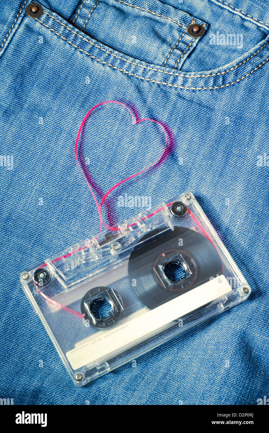 vintage audio cassette on blue jeans with red tape pulled out as heart shape Stock Photo