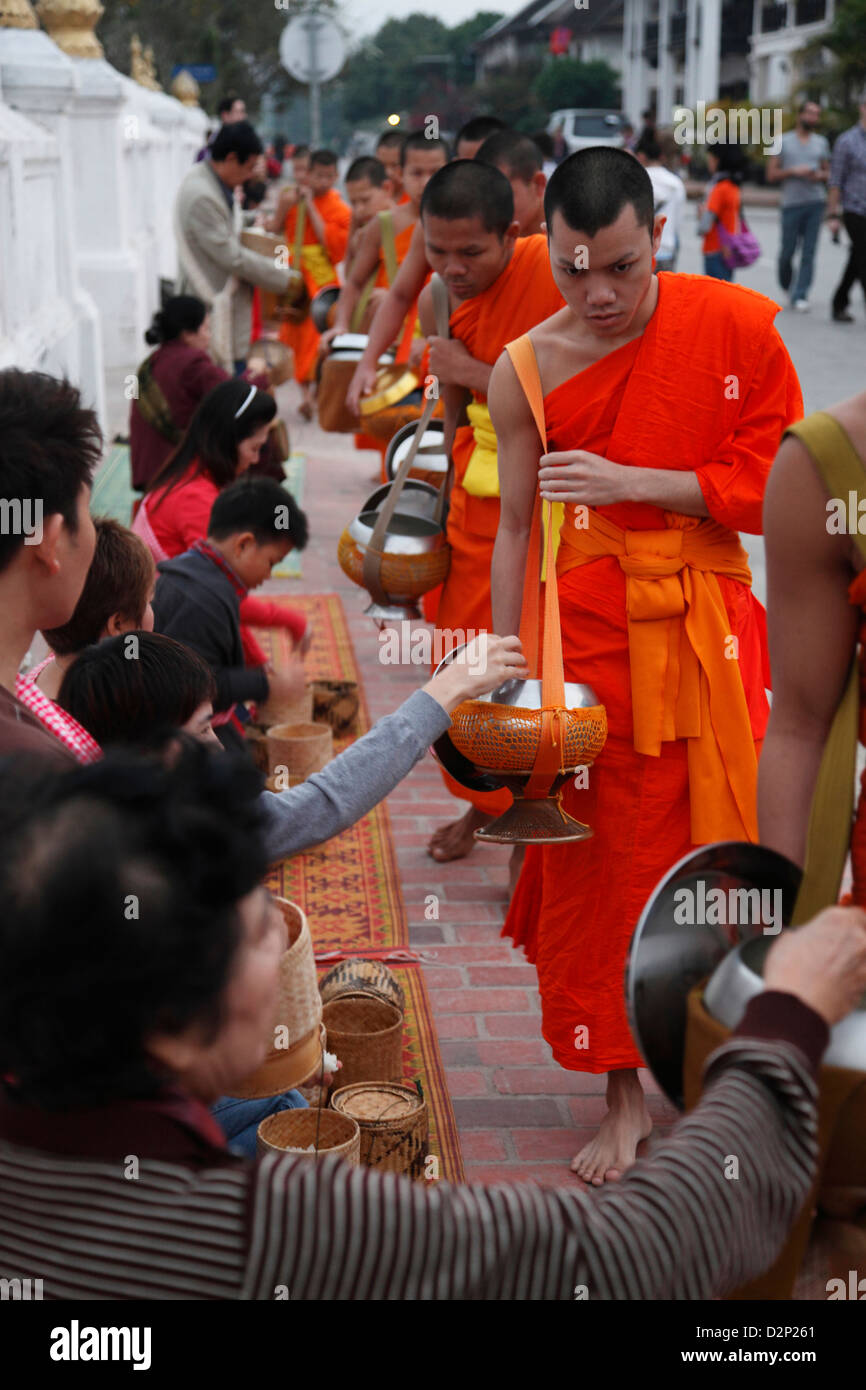 Monks wearing traditional saffron robes receiving alms at daybreak at Wat Saen temple. Stock Photo