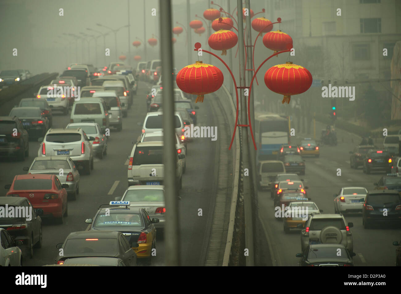 Chinese red lanterns are strung over heavy traffic in thick haze in Beijing,  China. 30-Jan-2013 Stock Photo