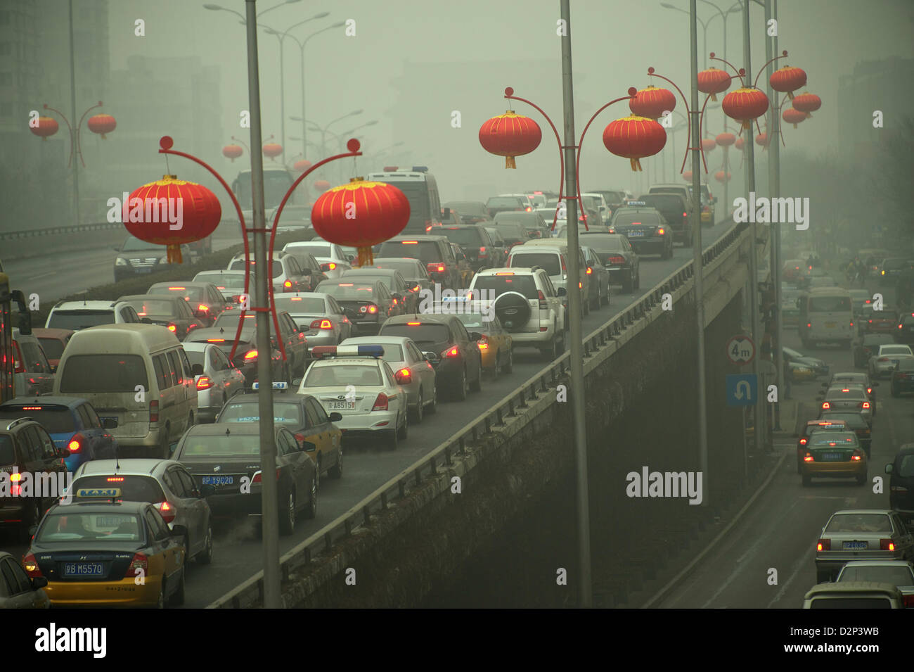 Chinese red lanterns are strung over heavy traffic in thick haze in Beijing,  China. 30-Jan-2013 Stock Photo