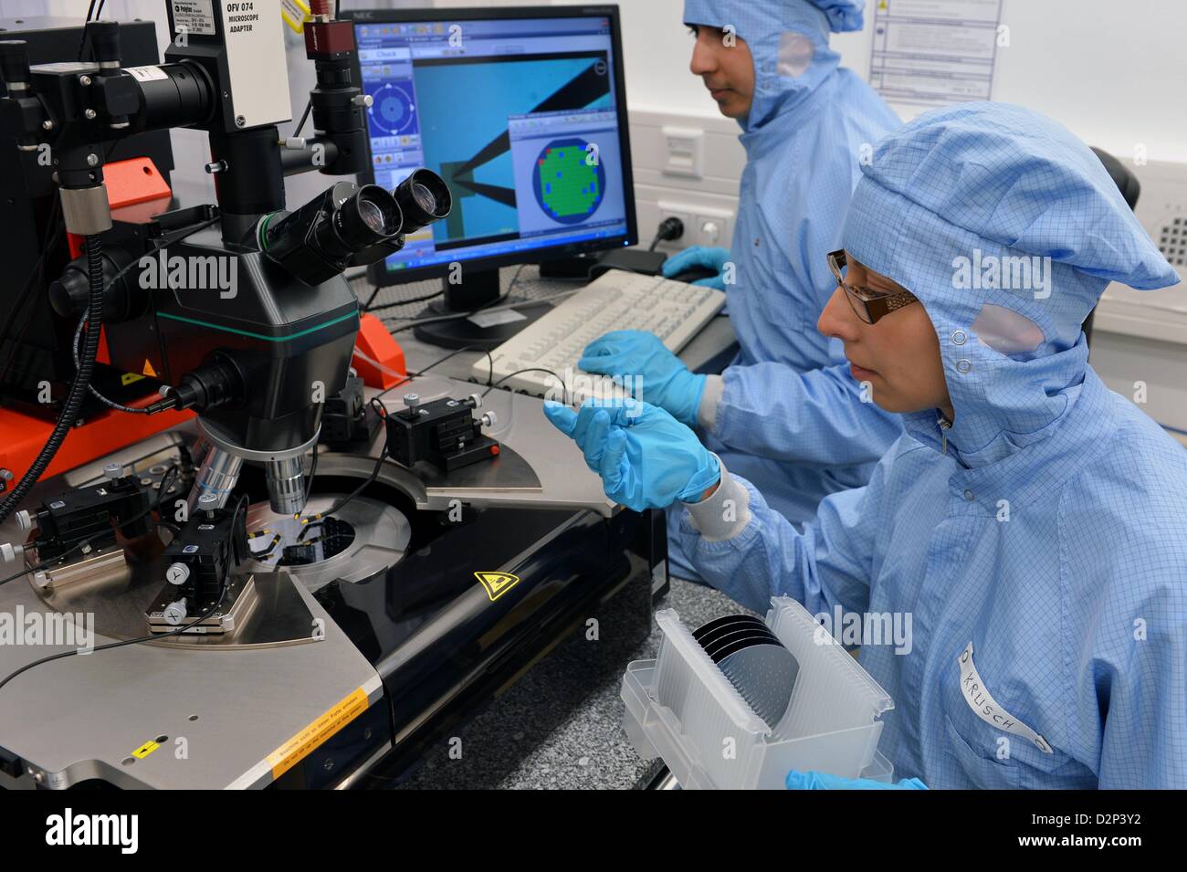 Employees Annett Krusch (R) and Dileep Dhakal put a 4-inch (100 mm) wafer into the wafer sample station at the Microtechnology  Laboratory of the Fraunhofer Institute for Electronic Nano Systems ENAS in Chemnitz, Germany, 04 December 2012. The researchers contribute to the German Federal Cluster of Excellence 'Merge Technologies for Multifunctional Lightweight Structures'. The German Federal Cluster of Excellence MERGE is a prime example for an interdisciplinary research project at the Chemnitz University of Technology, which will be officially launched on 30 January 2013. Photo: Hendrik Schmi Stock Photo