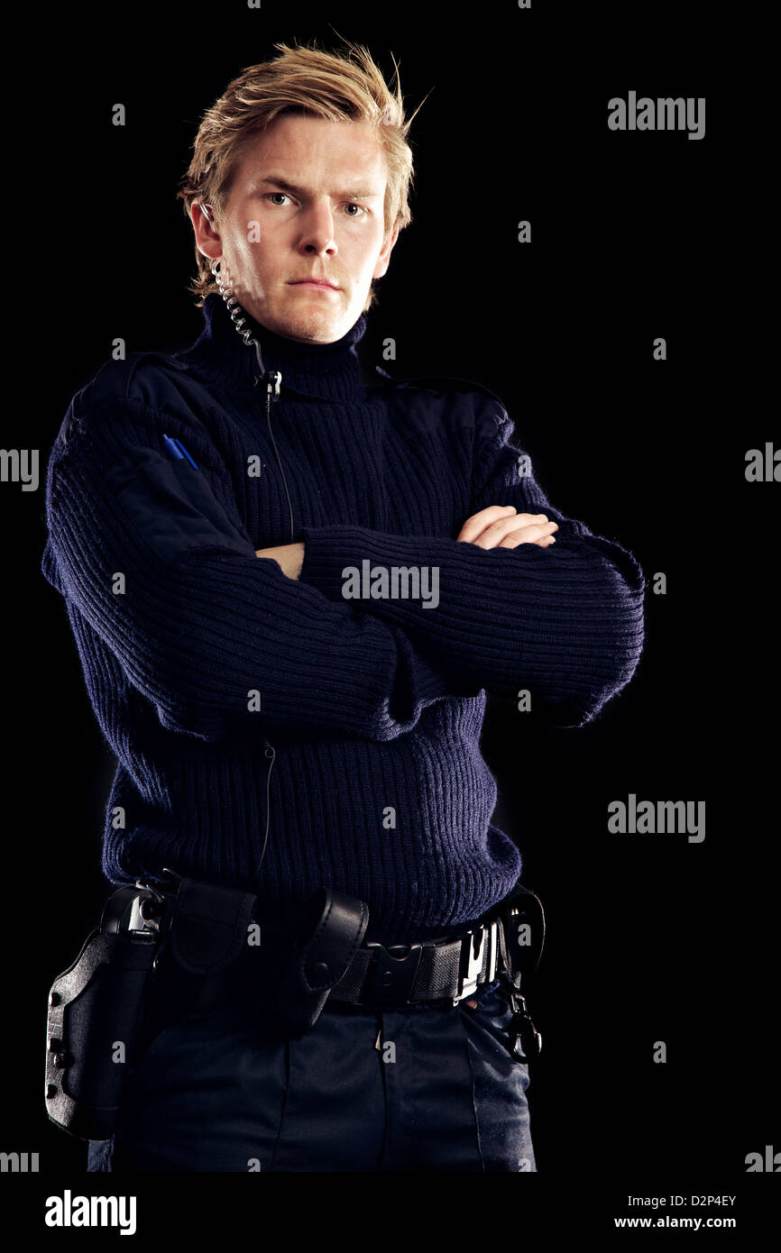 Serious police officer against black background ensuring we are safe from criminals Stock Photo