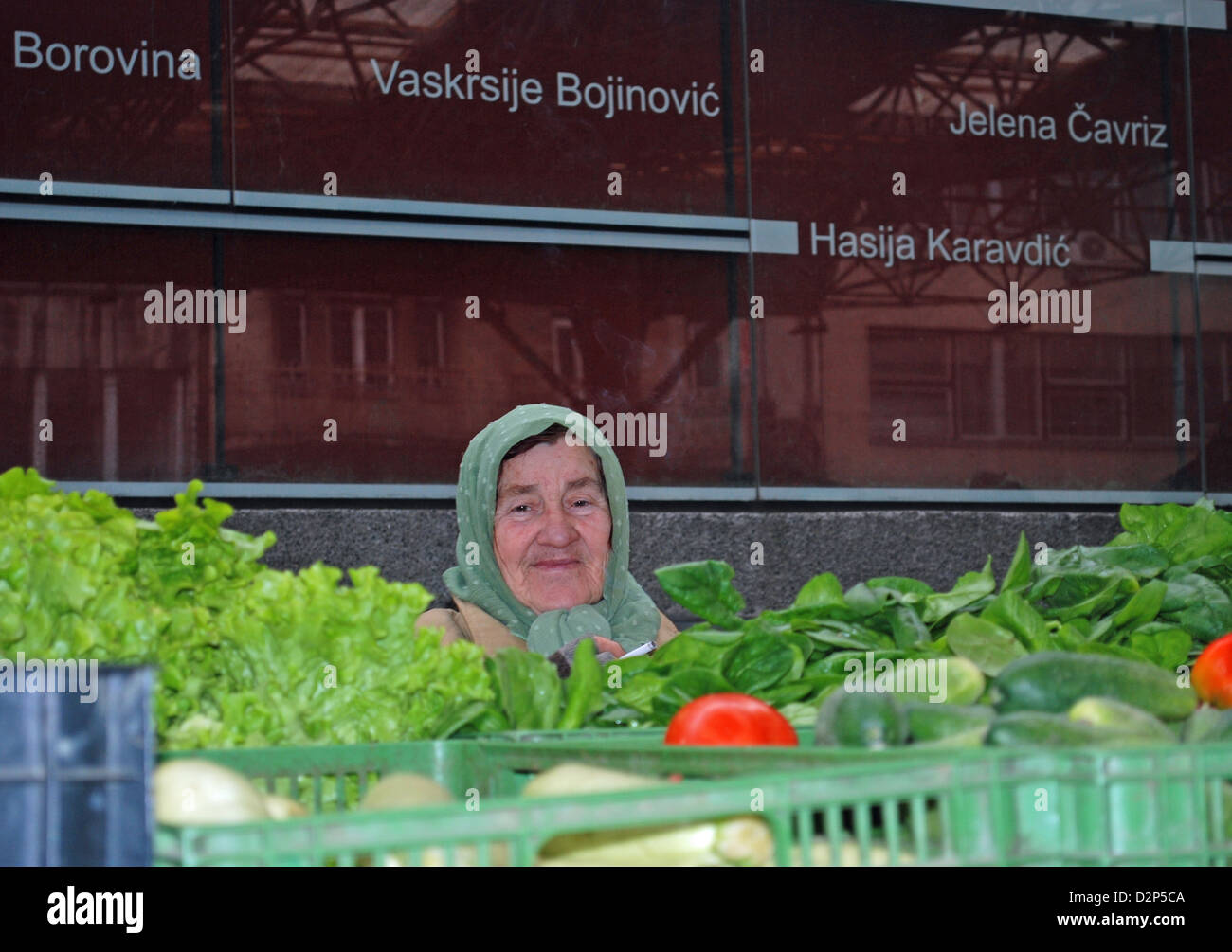 A vegetable seller in front of memorial wall to those who were killed and injured during 1994 Markale marketplace massacre. Stock Photo