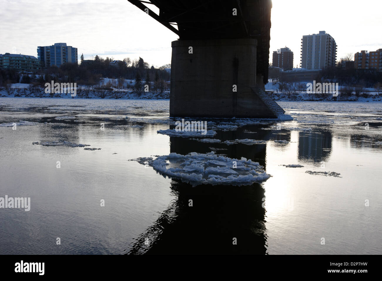 large chunks of floating ice on the south saskatchewan river in winter flowing under traffic bridge Saskatoon Saskatchewan Canad Stock Photo