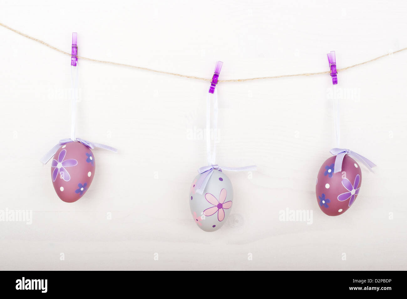 Purple Easter eggs hanging on a rope on clothespins, wooden background Stock Photo