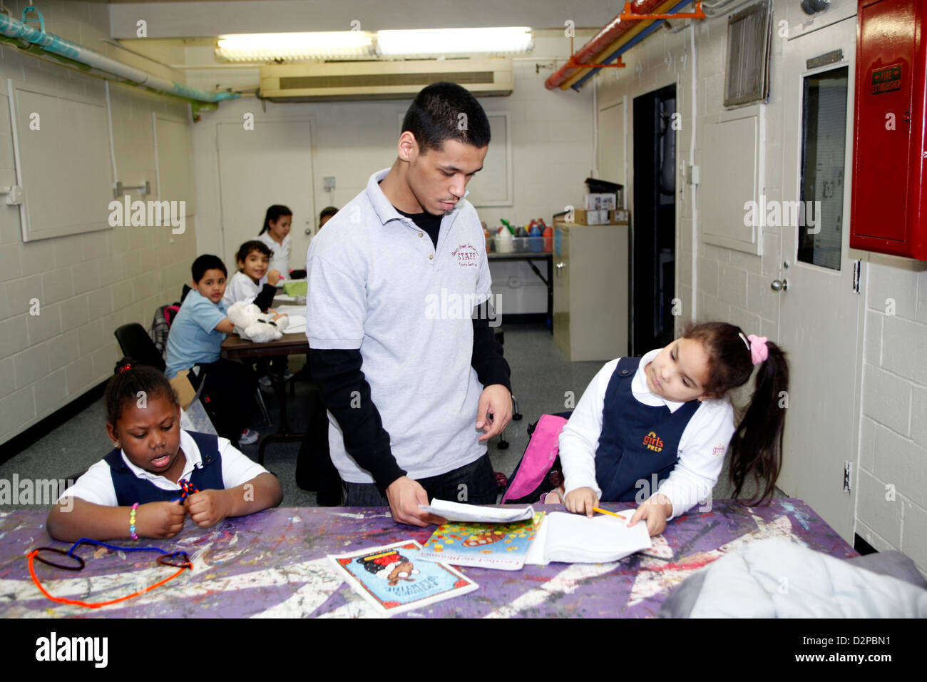 High school age boy works with younger children in an educational after school program in NYC Stock Photo