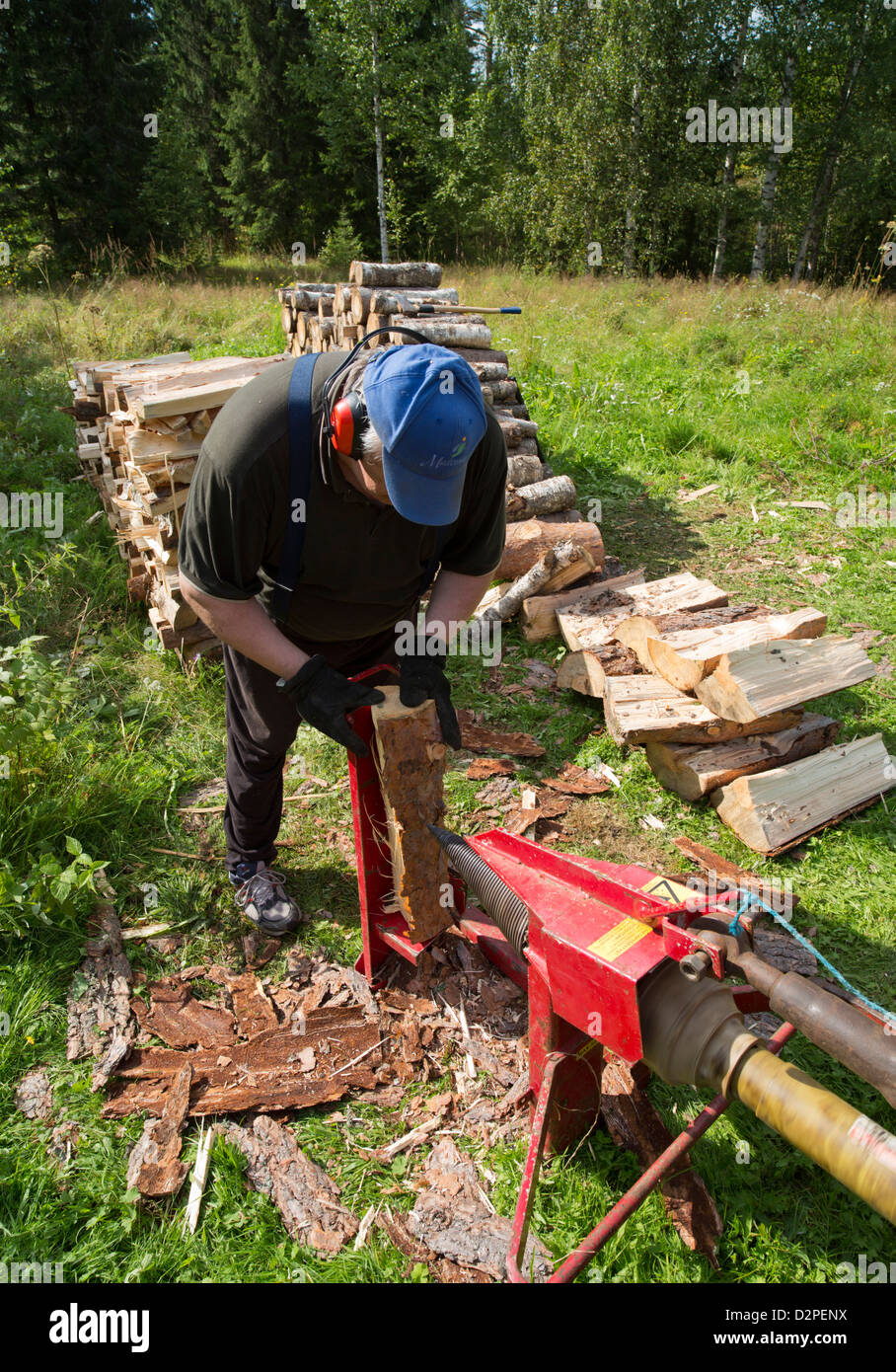 Elderly man splitting wood to firewood with tractor powered screw log  splitter , Finland Stock Photo - Alamy