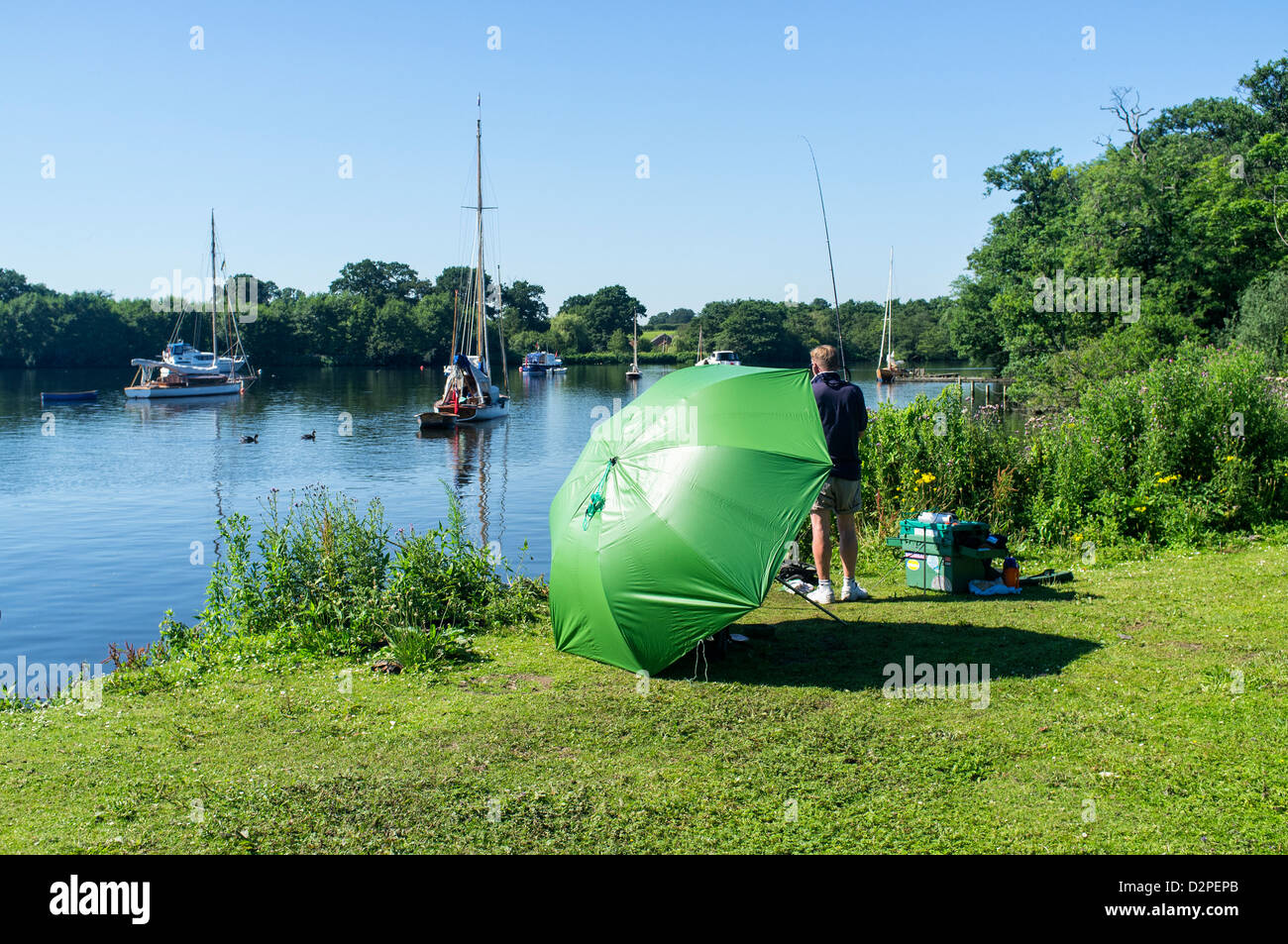 Fisherman Sitting under Green Umbrella at Wroxham Broad Norfolk Stock Photo