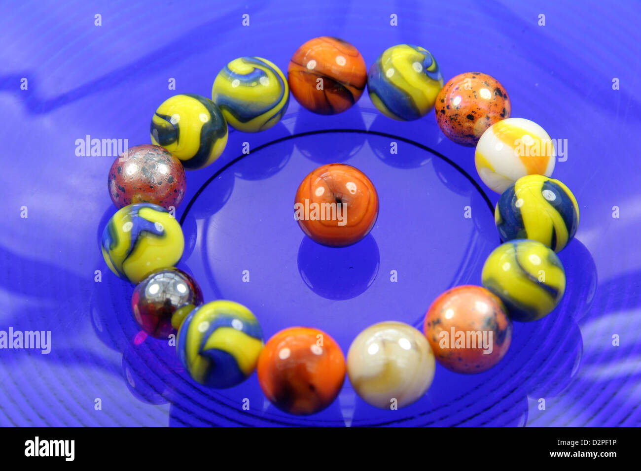 A ring of blue,yellow and orange marbles on a blue glass background
