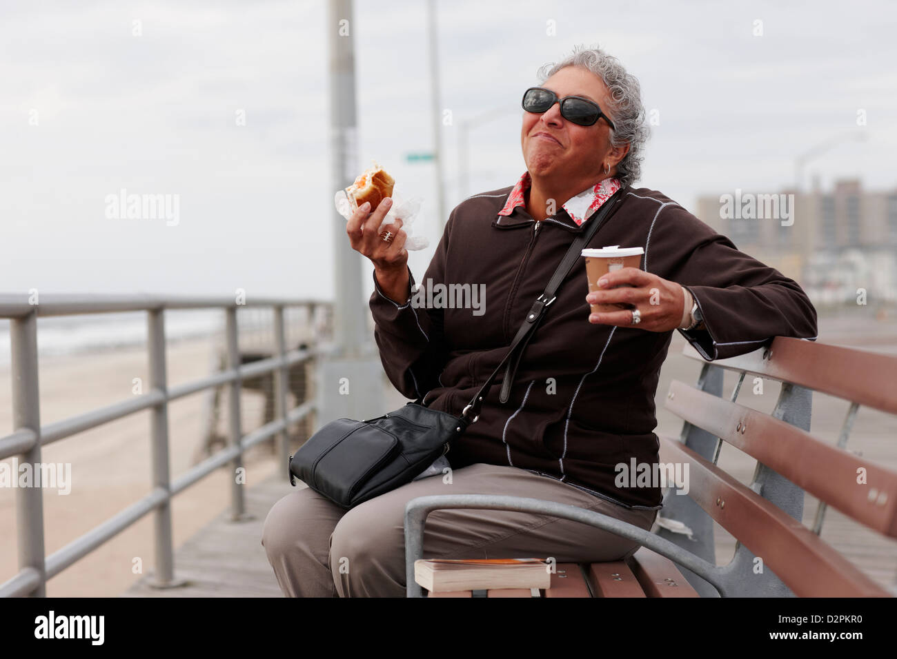 Women eating pastry and drinking coffee on boardwalk Stock Photo