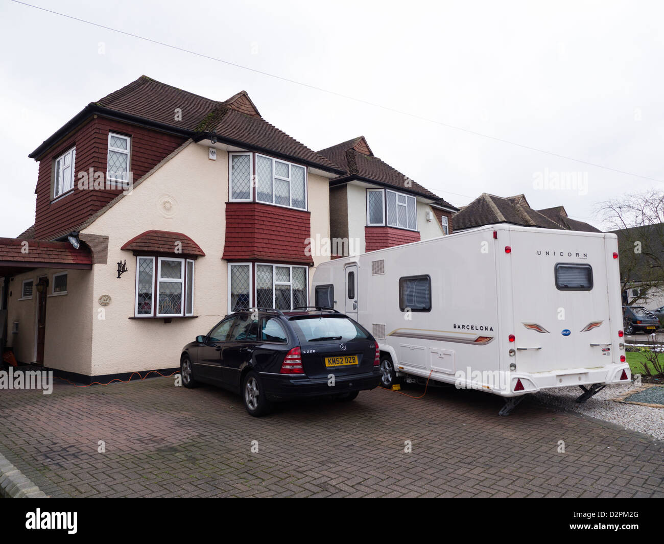 A large caravan parked in the front garden of a 20s or 30s suburban house Stock Photo