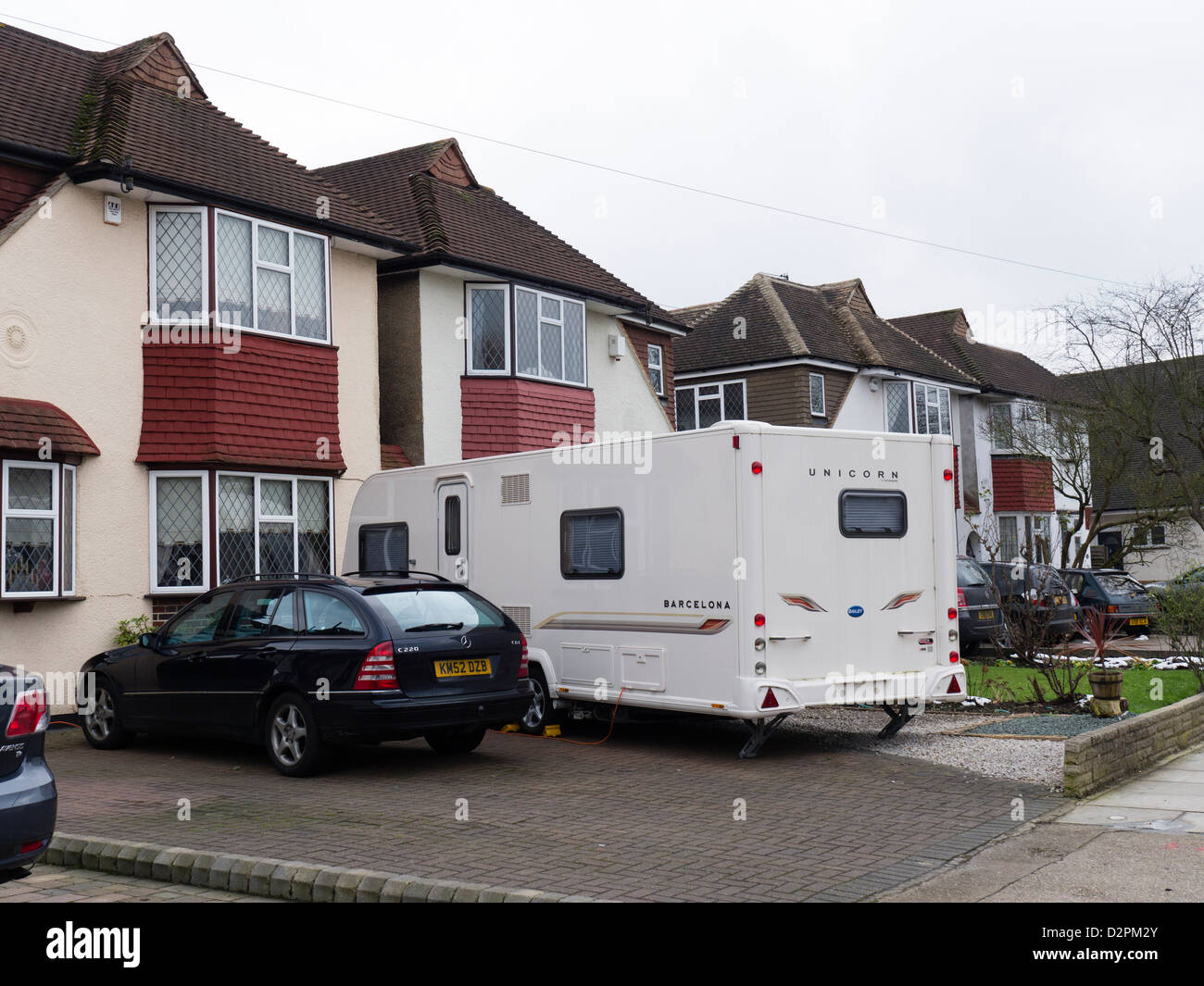 A large caravan parked in the front garden of a 20s or 30s suburban house Stock Photo