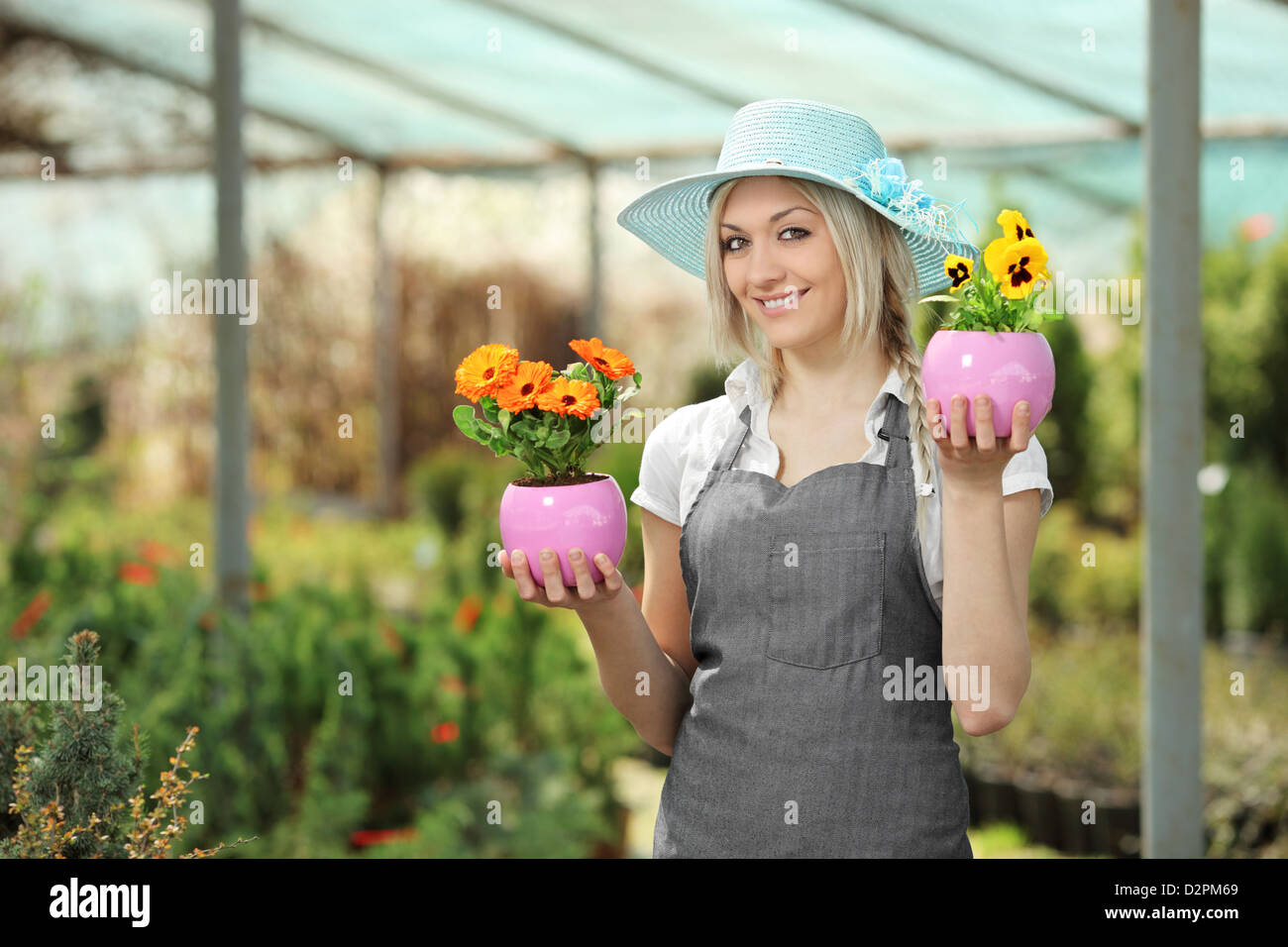 Young female gardener holding flower pots in a garden Stock Photo - Alamy
