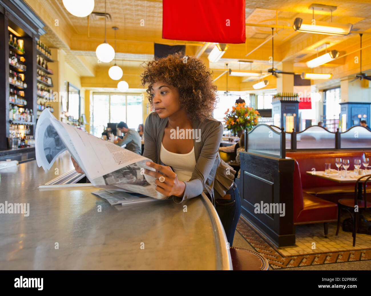 African American woman reading newspaper in cafe Stock Photo