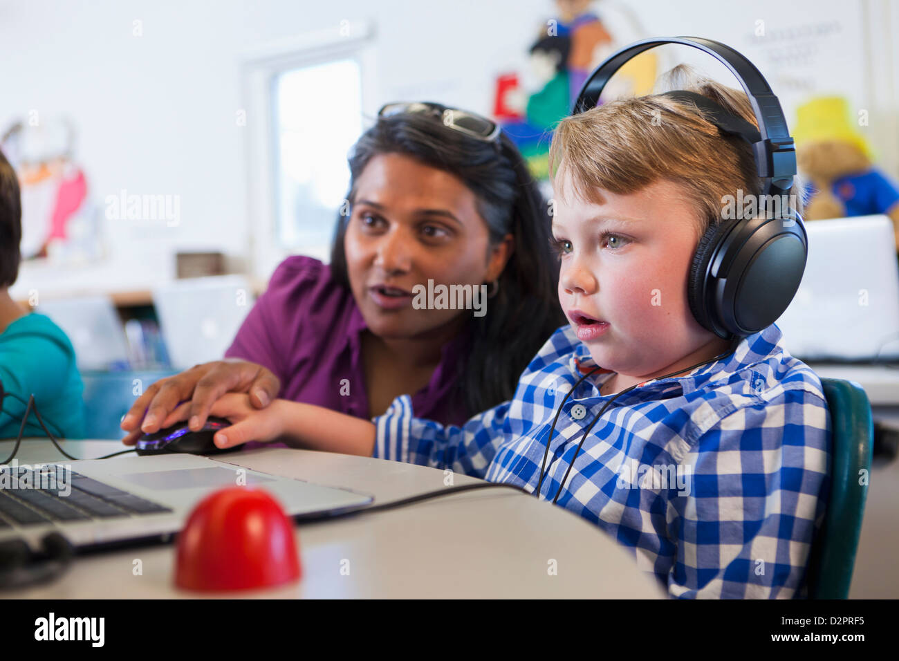 Teacher helping student using laptop Stock Photo