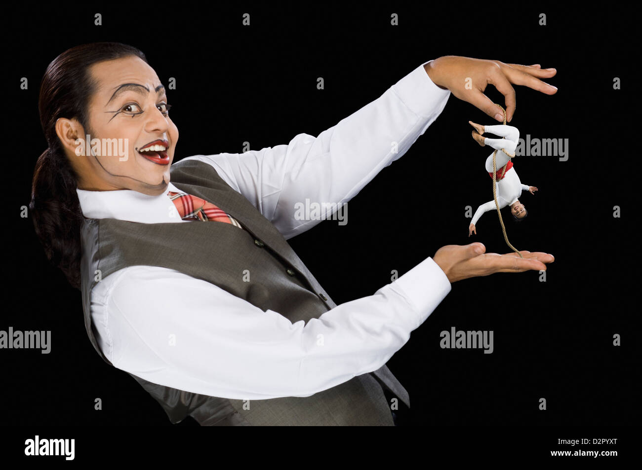 Portrait of a mime holding a rope with two acrobat performing on it ...