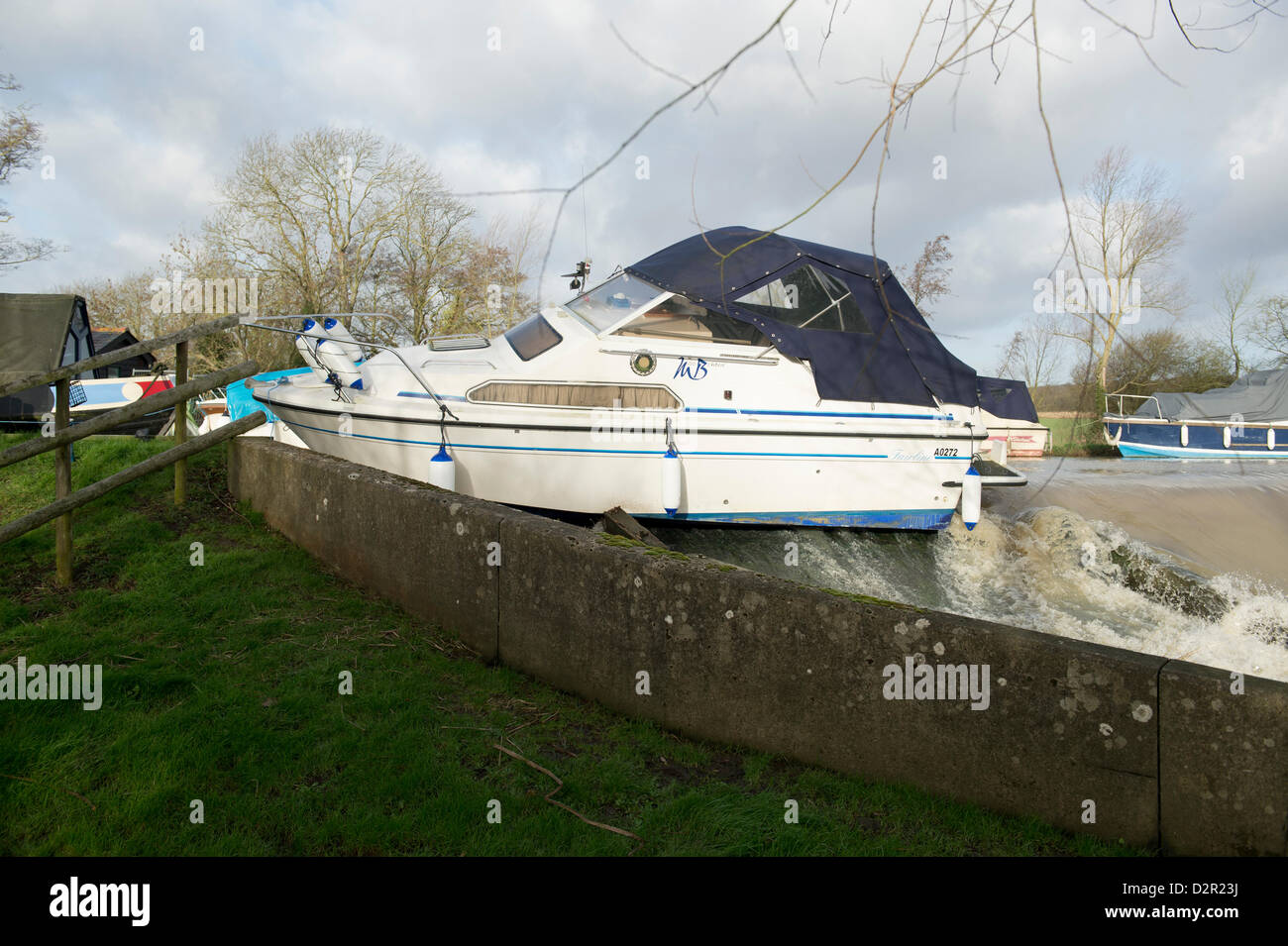 Little Baddow, Essex, UK. 31st January 2013.  A motor cruiser, Miss Behavin', sits precariously on a weir at Paper Mill Lock. The river is very high and fast after recent rain and snow melt. Officers from Essex Waterways have secured the vessel and are waiting to recover it. It is believed that vandals have taken the mooring ropes, as the boat has drifted 200m and ropes cannot be found. Allsorts Stock Photo/Alamy Live News Stock Photo