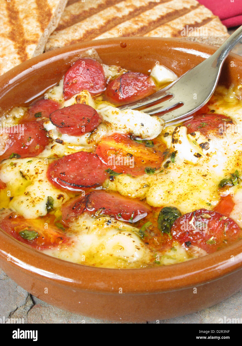 A typical Greek dish of saganaki (baked cheese) with loukanika (spicy ...