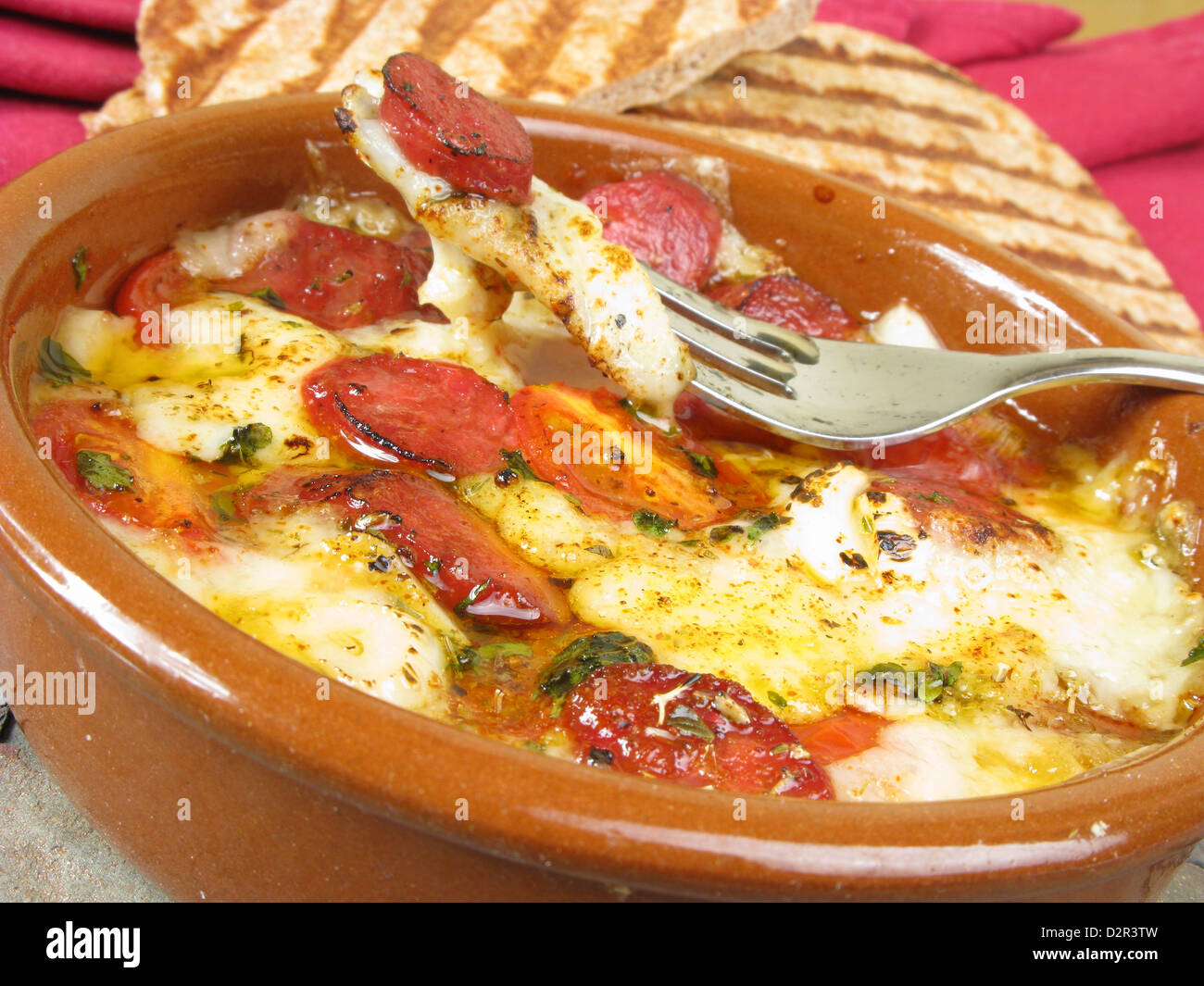 A typical Greek dish of saganaki (baked cheese) with loukanika (spicy ...